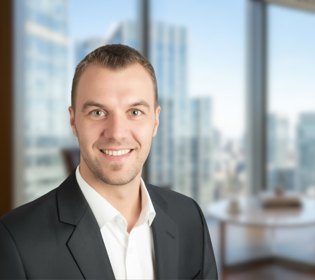 Roland Unger lächelnd vor einem hellen Office-Hintergrund. Er trägt ein weißes Hemd und einen anthrazitfarbenen Anzug.