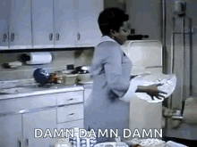 A woman in a white coat stands in a kitchen, visibly surprised or shocked, with a caption that says 'DAMN DAMN DAMN'.