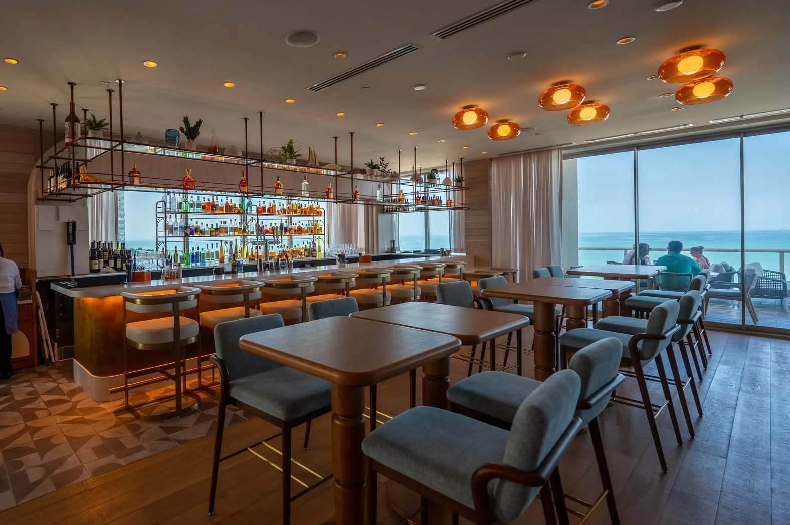 People sitting on barstools at a well-lit cocktail lounge.