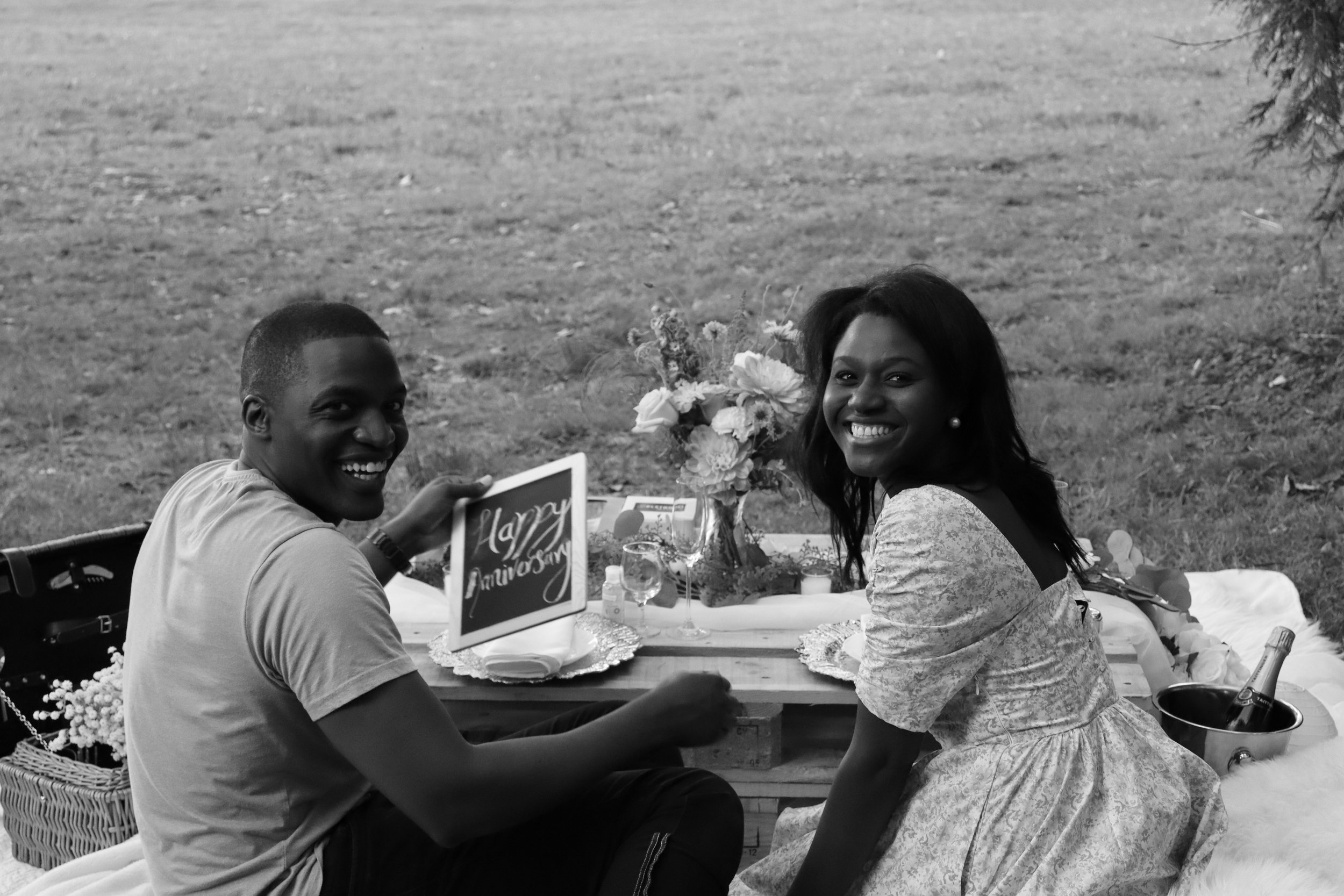 Ona Events luxury picnic in Vancouver, Canada featuring a smiling couple sitting on a picnic blanket outdoors, celebrating their anniversary.