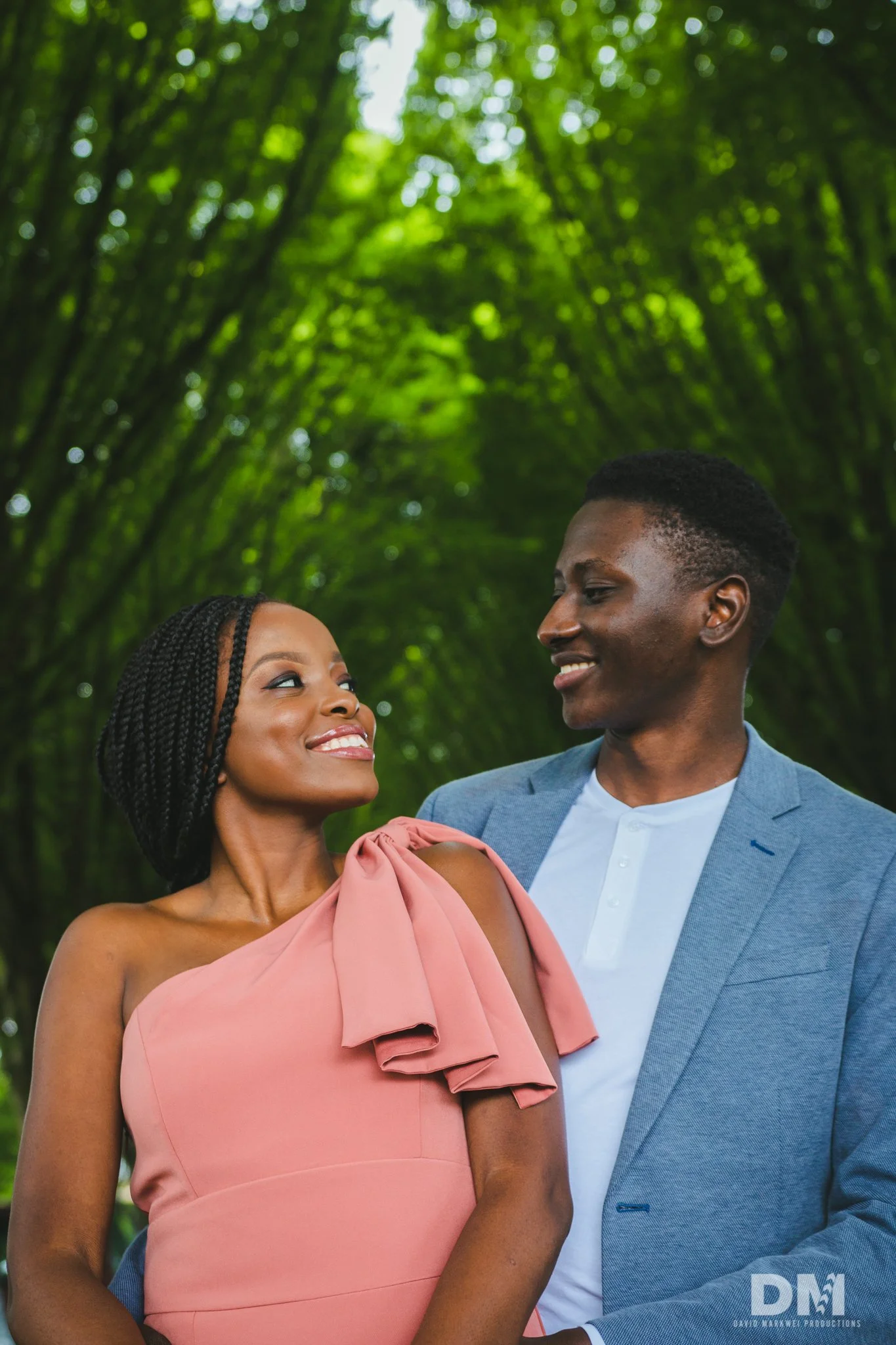 Ona Events smiling couple looking at each other outdoors in front of green trees, posing for their engagement photoshoot, engagement party planned by Ona Events, Vancouver event planner.