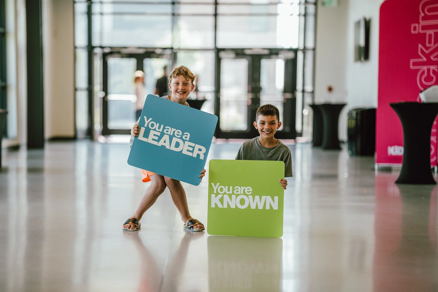 Two kids holding signs that say You are a leader and You are known