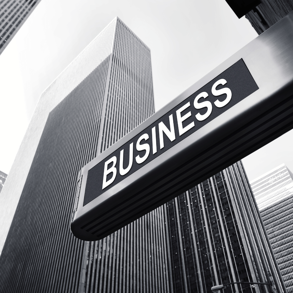 Black and white photo of a tall skyscraper and a business sign in an urban setting.
