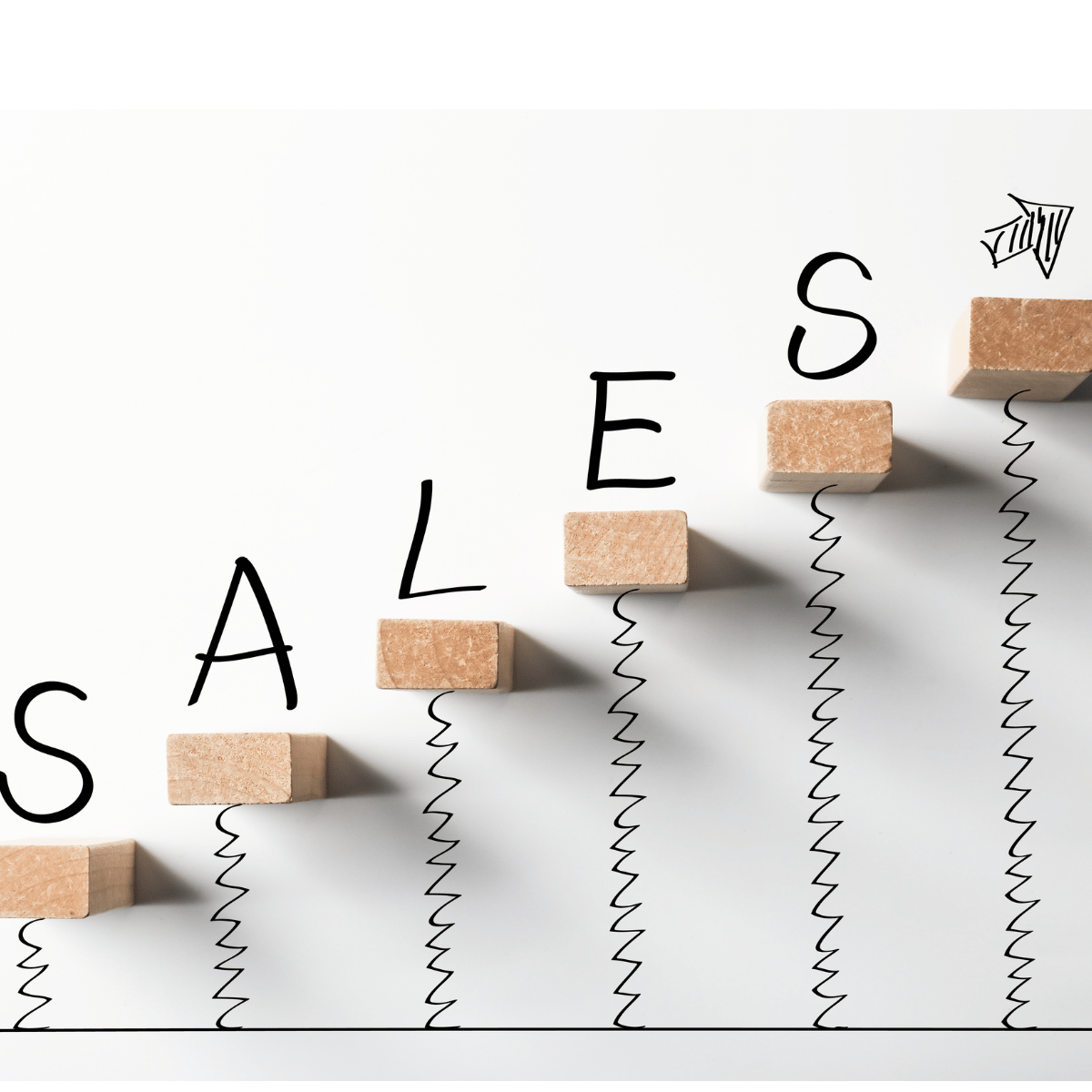 Wooden blocks arranged to spell 'SALES' with hand-drawn arrows and zigzag lines connecting each letter, symbolizing growth or increase.