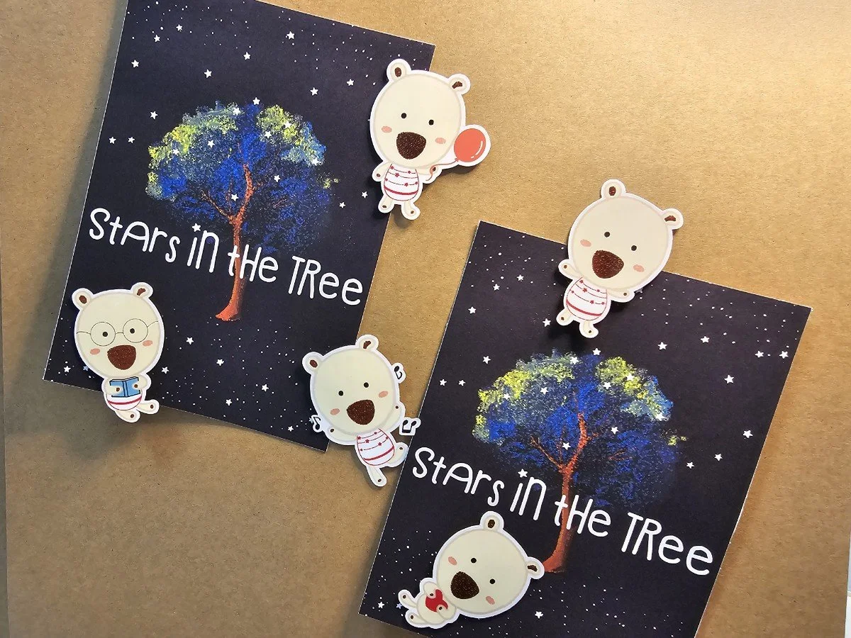 Two cards with a starry night background and a colorful tree, featuring the text "Stars in the Tree," decorated with bear-themed paper clips, some with glasses, some holding items like a lollipop and a fish.