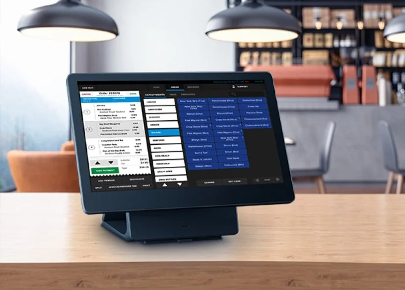Point of sale system on a wooden counter in a cafe setting.