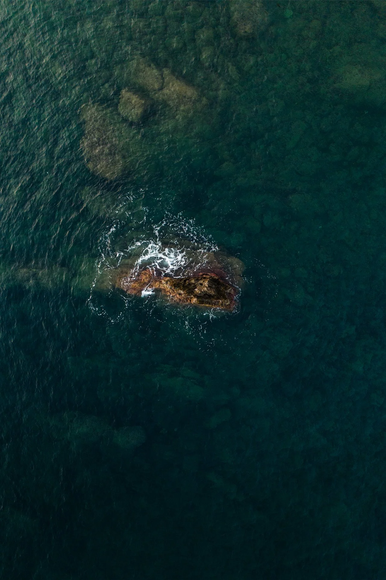 Vista dall'alto di una roccia nel mare con acqua verde e blu