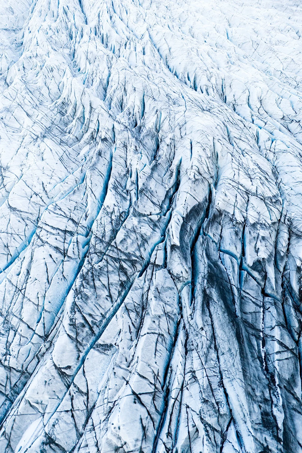 Foto di un ghiacciaio con grandi crepe e parti di ghiaccio azzurro e bianco.