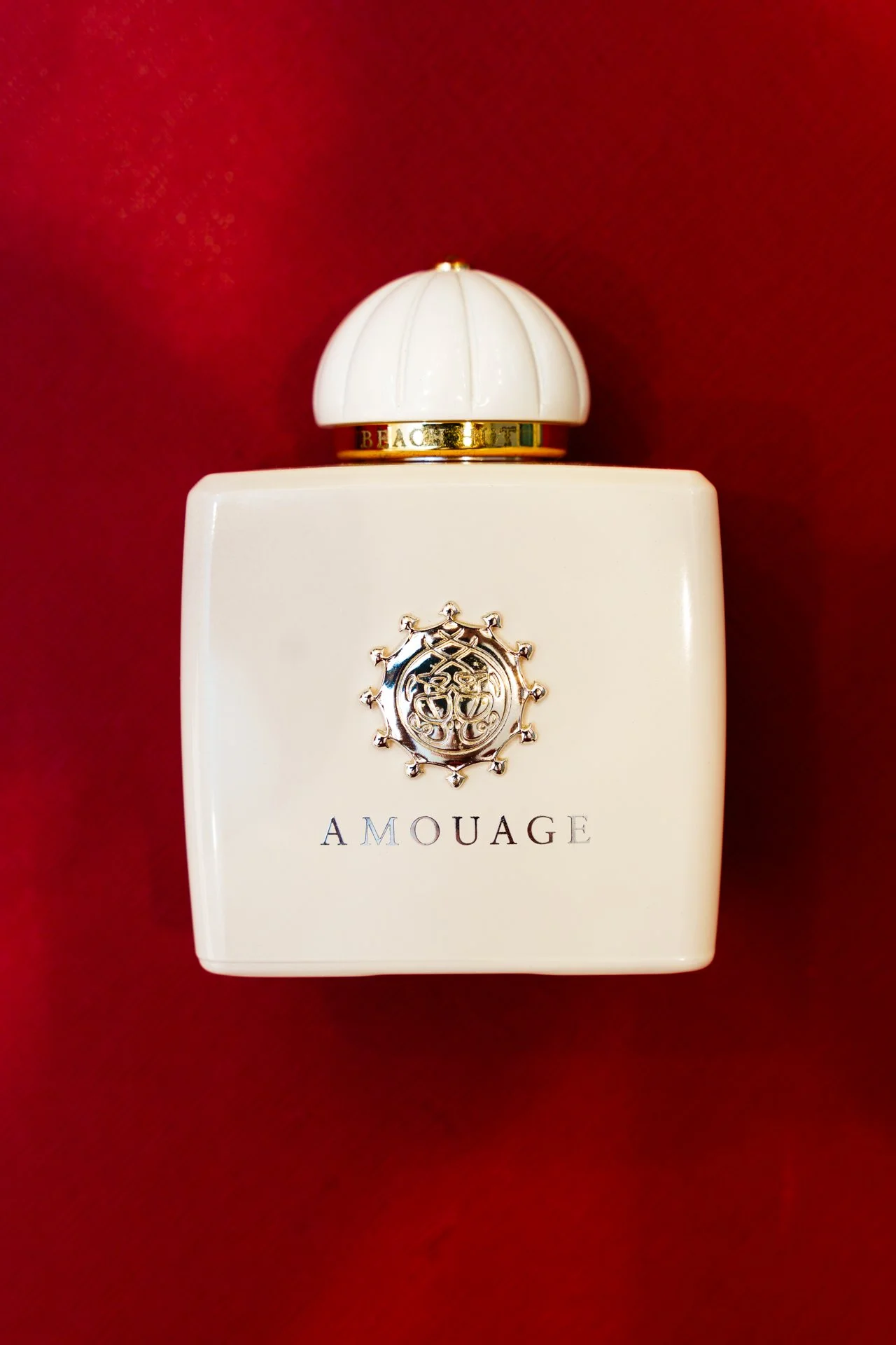 Flacone di profumo bianco con coperchio decorativo in rilievo, sfondo rosso