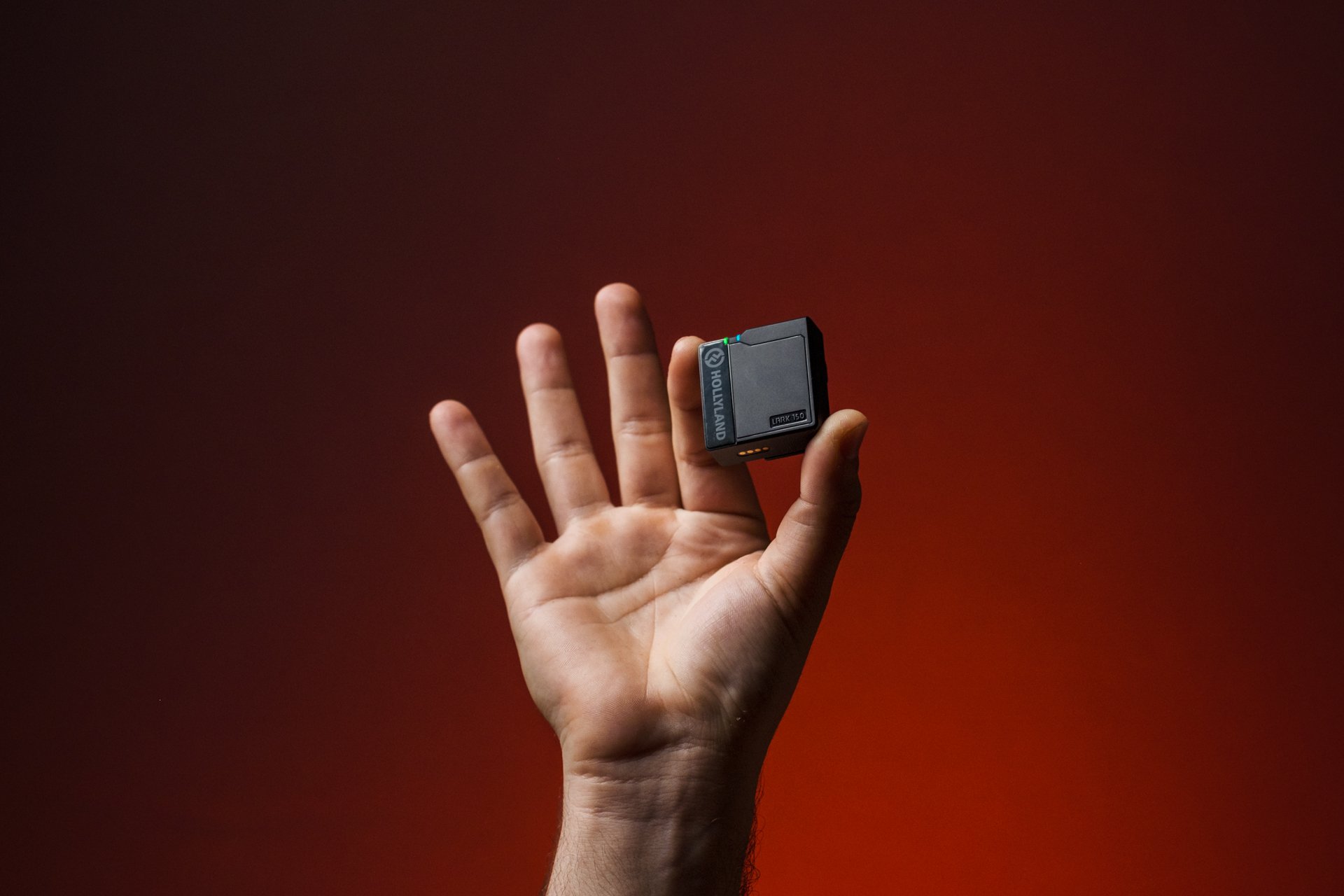 Una mano tiene una batteria portatile di colore nero con uno sfondo rosso scuro.