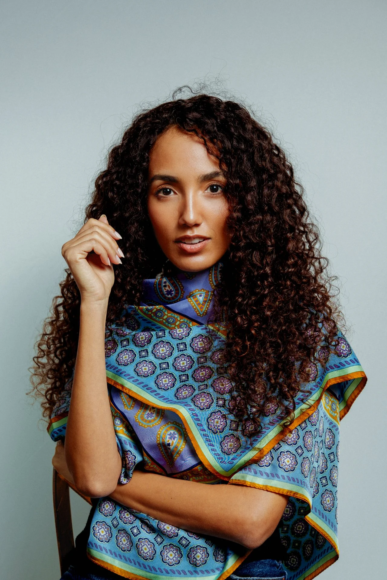 Ritratto di una donna con capelli ricci che indossa una sciarpa colorata con motivi geometrici.