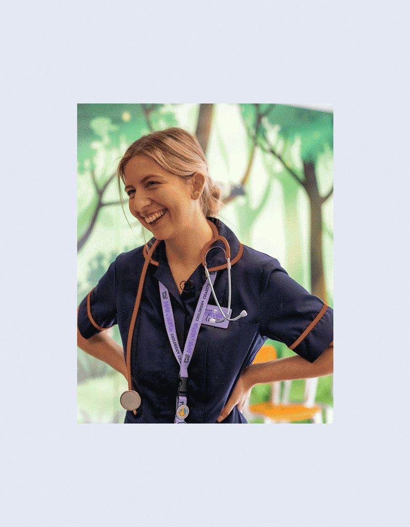 Smiling nurse wearing a stethoscope and a lanyard in a healthcare setting.
