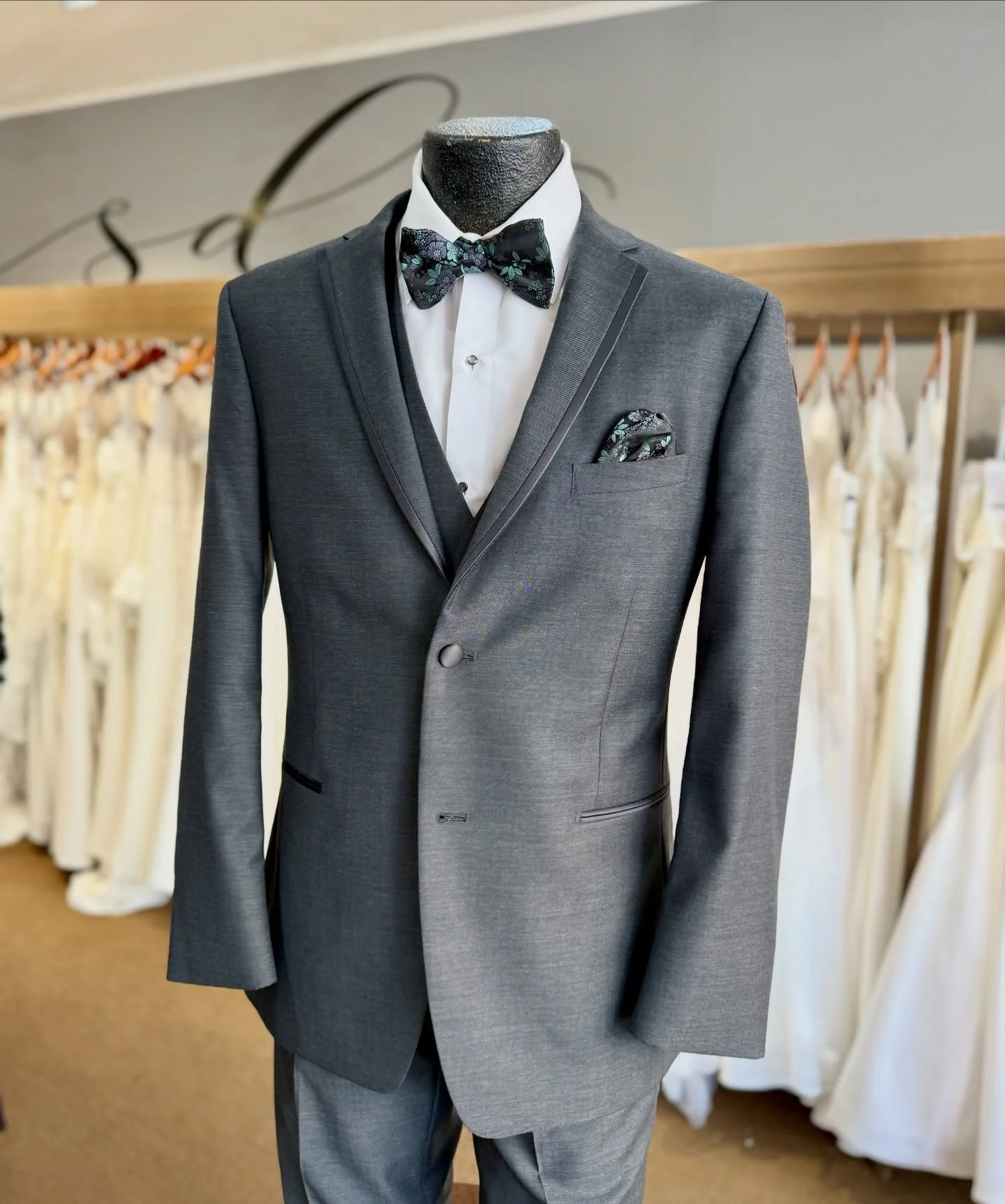 A gray tuxedo with a black floral bow tie, white shirt, and matching pocket square.