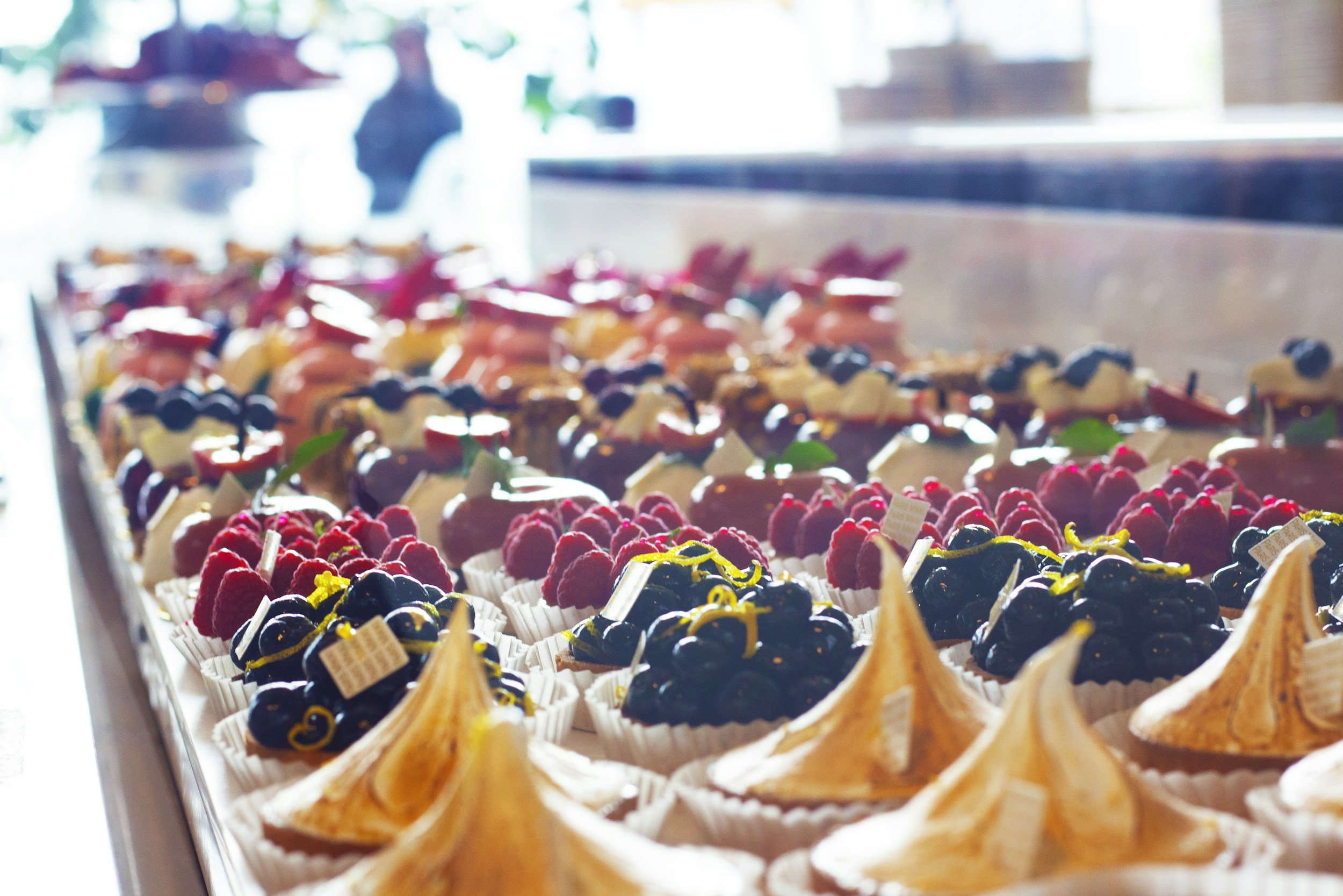 Display of assorted pastries and desserts with berries and meringue in a bakery.