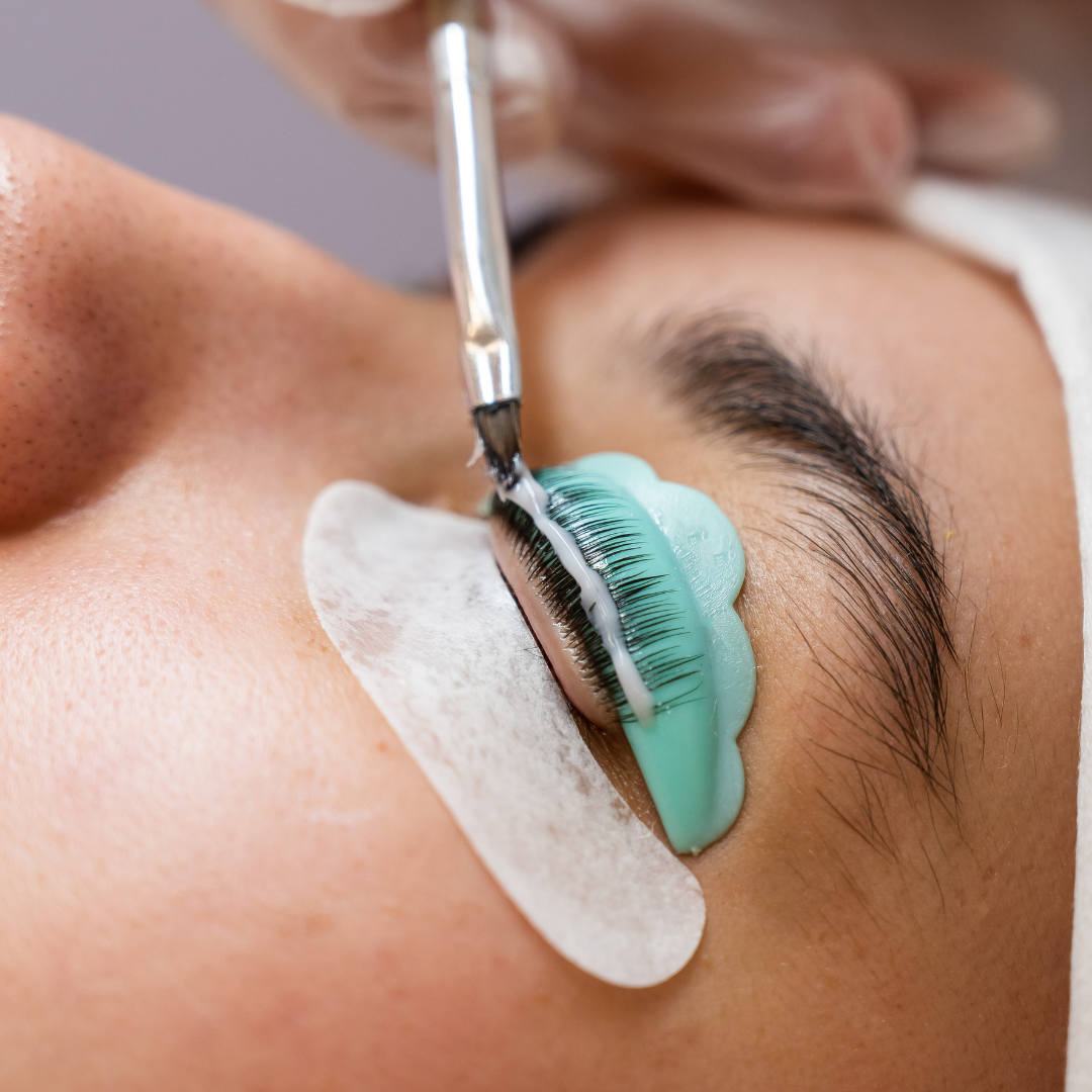 Close-up of an eye receiving a lash lift treatment with a silicone pad and applicator brush.