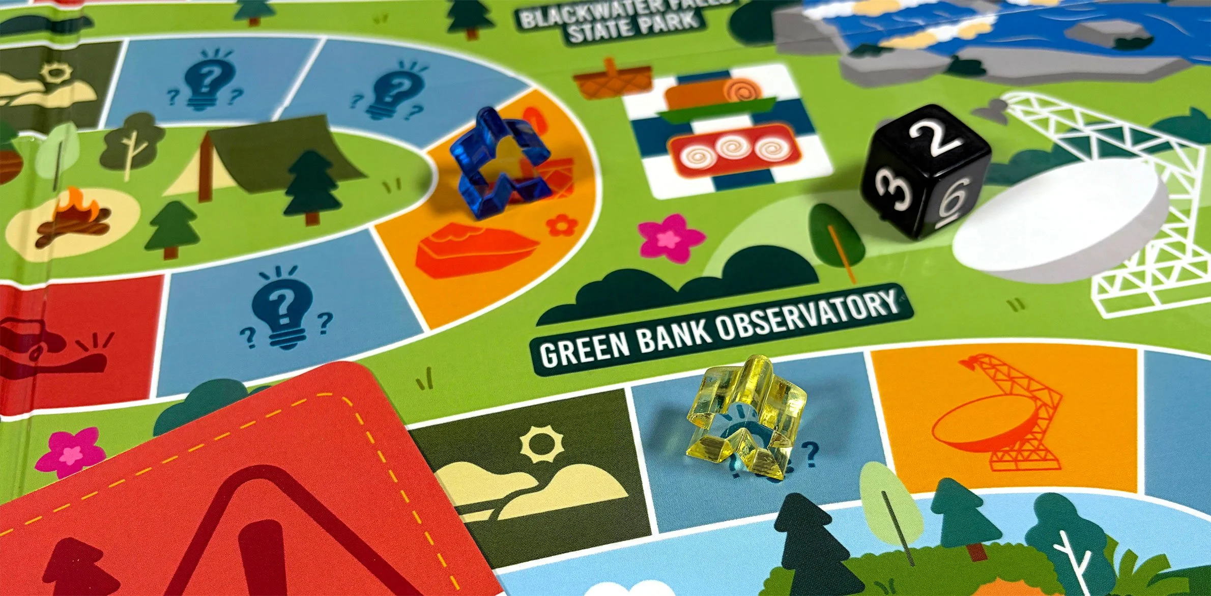Close-up of a colorful board game with game pieces, dice, and a section labeled 'Green Bank Observatory' at Blackwater Falls State Park.
