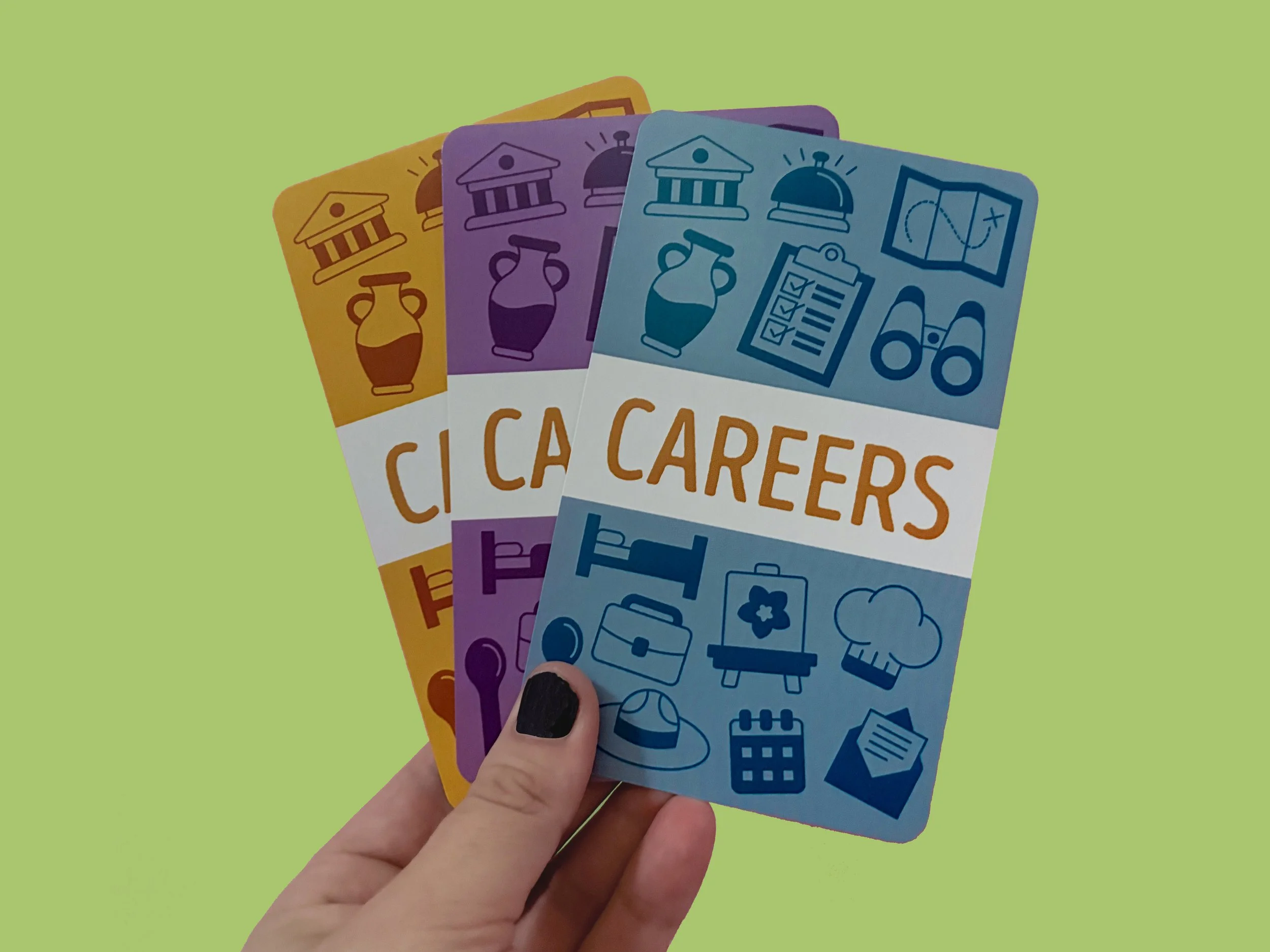 A hand holding four colorful cards with icons related to careers against a green background.
