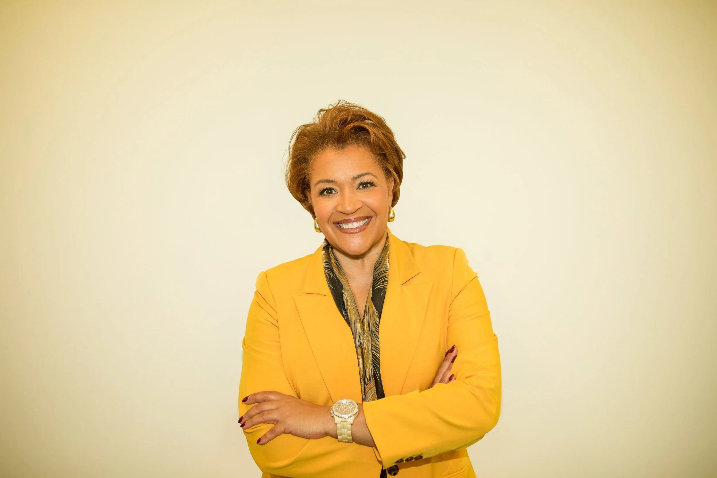 Leilani in a yellow blazer smiling with arms folded
