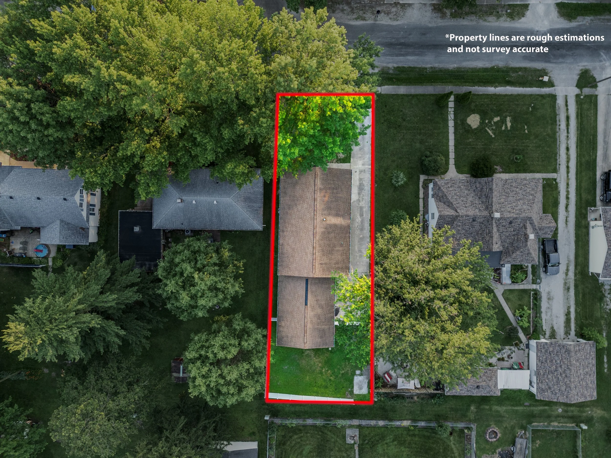 Aerial view of a residential property outlined with a red border, showing a house with a brown roof, a driveway, trees, and neighboring houses with yards.