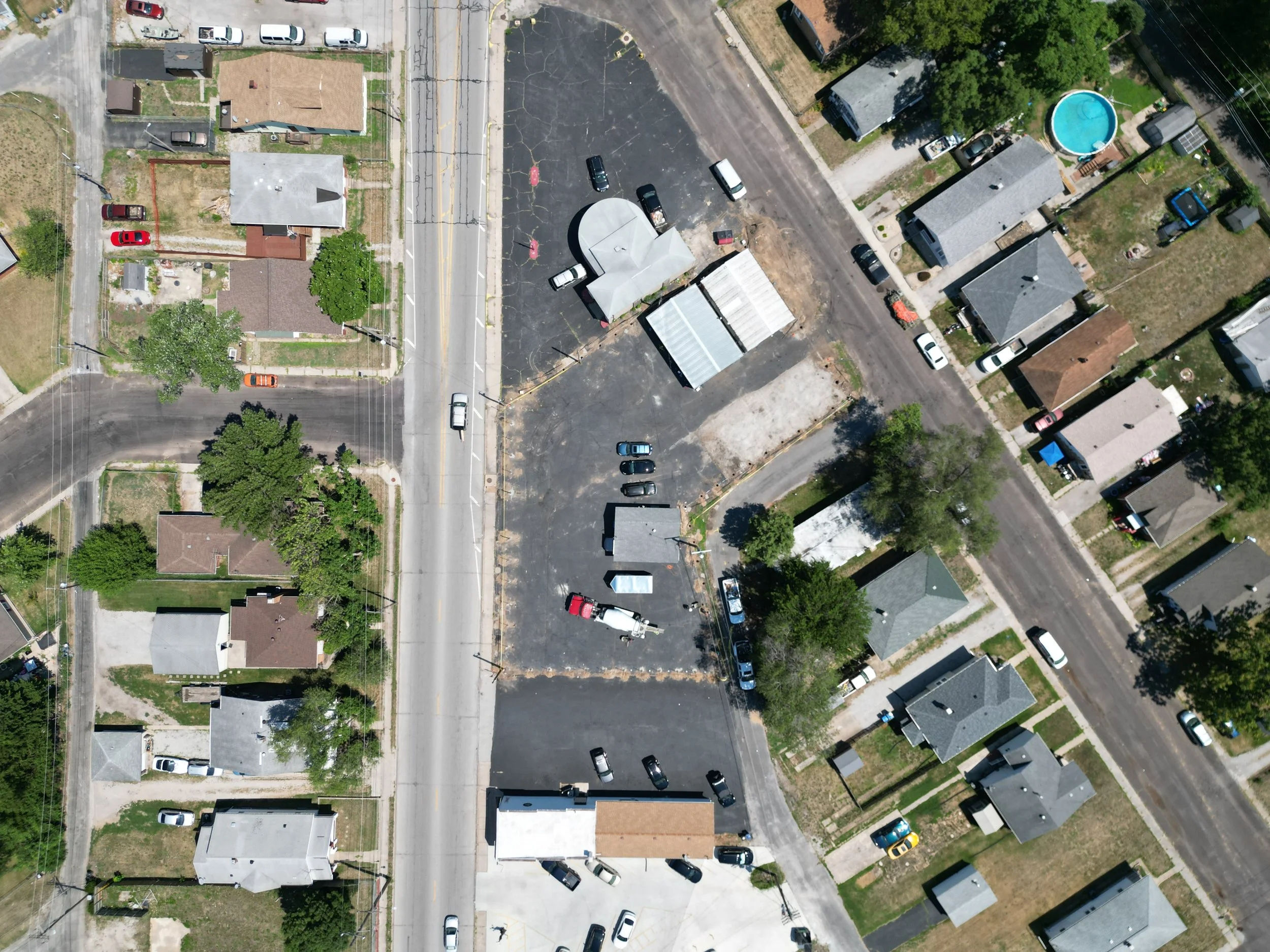 Aerial view of a neighborhood with houses, trees, parking lot, and streets.