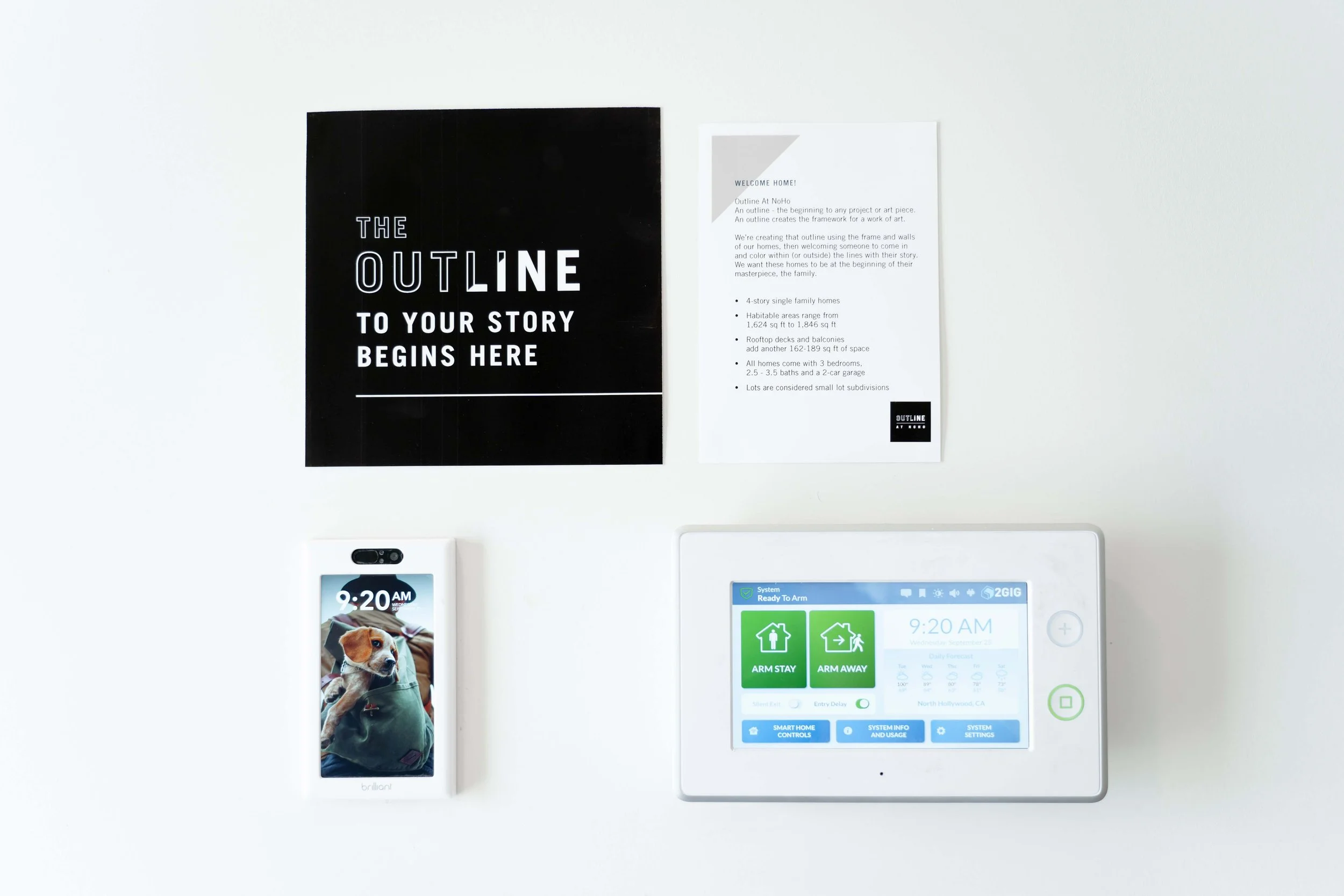 Wall with two notices and two electronic control panels; one is a smart home control panel, the other is a smartphone with a pet photo, all on a white wall. Home interior signage for self directed open houses