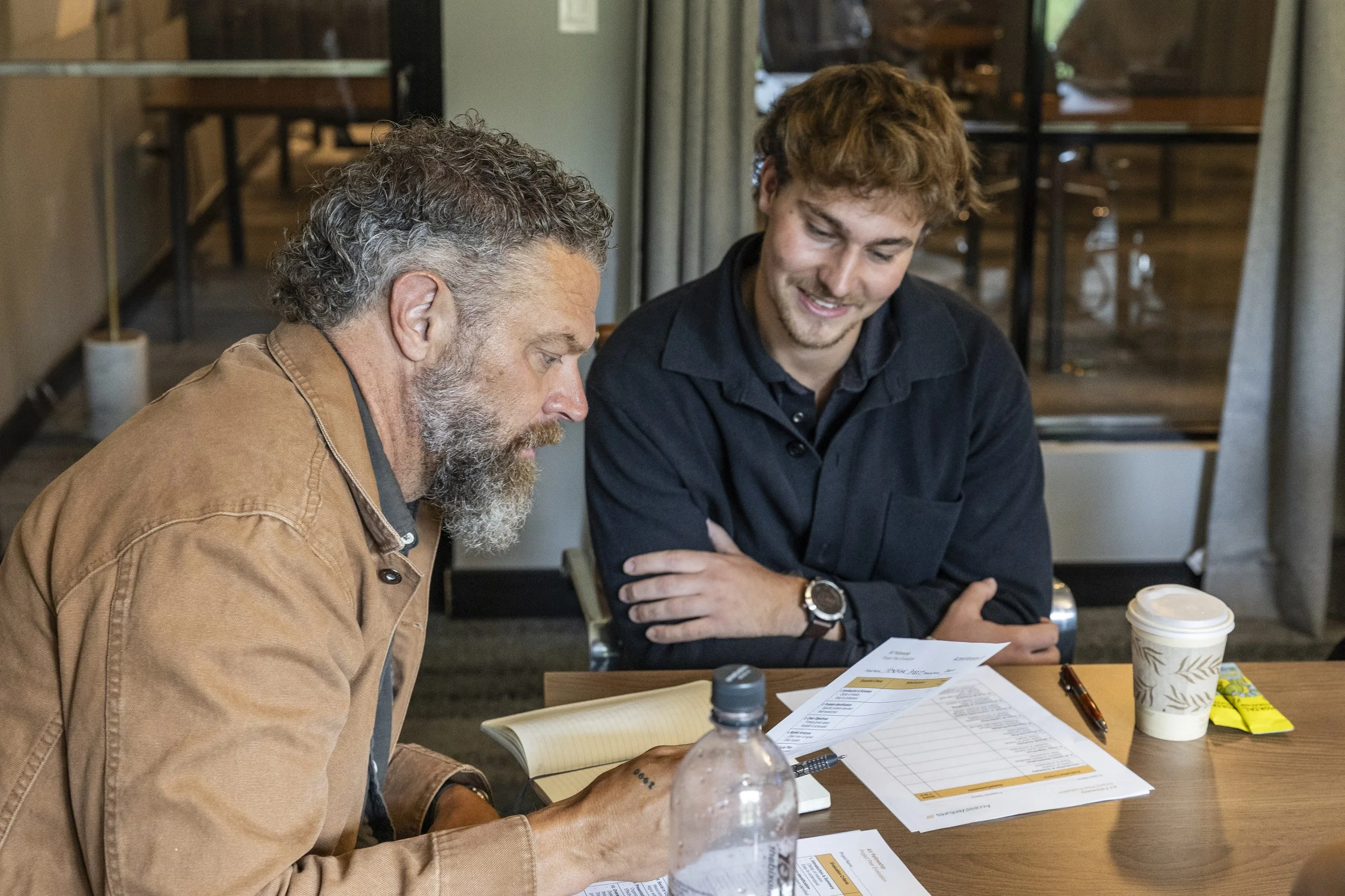 A woman giving a presentation on sustainable food systems standing in front of a screen displaying the topic. There is a table with snacks and drinks in the background.