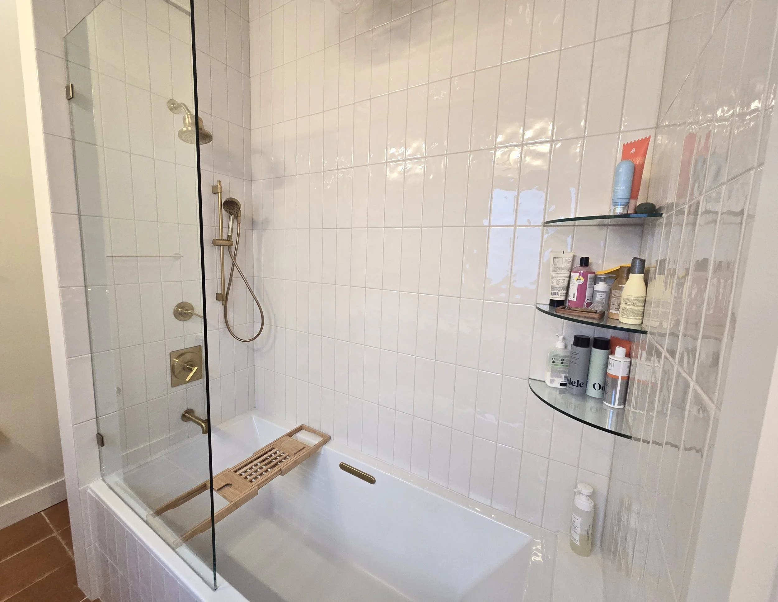 Custom primary shower tub with glass corner shelves