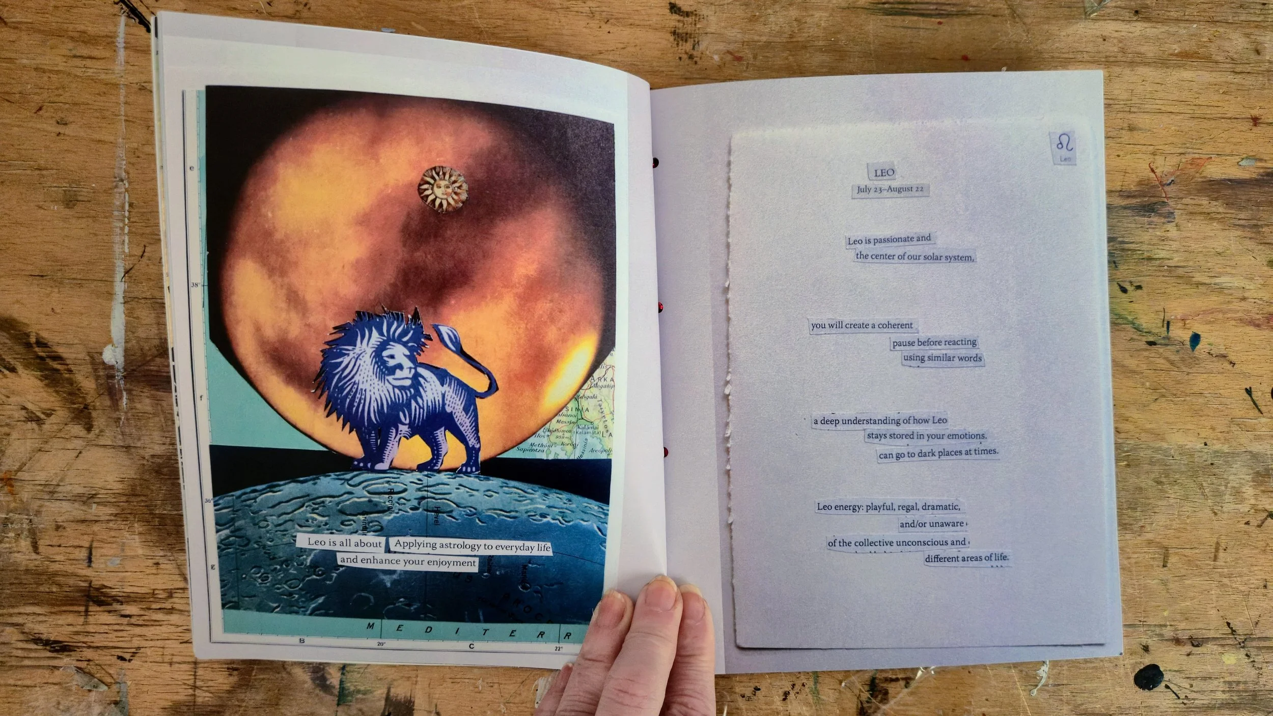 An open book on a wooden table, showing a collage on the left page with a large apple-like image featuring a small circular item at its center and a blue lion illustration at the bottom. The right page contains typed text about Leo astrology, with so