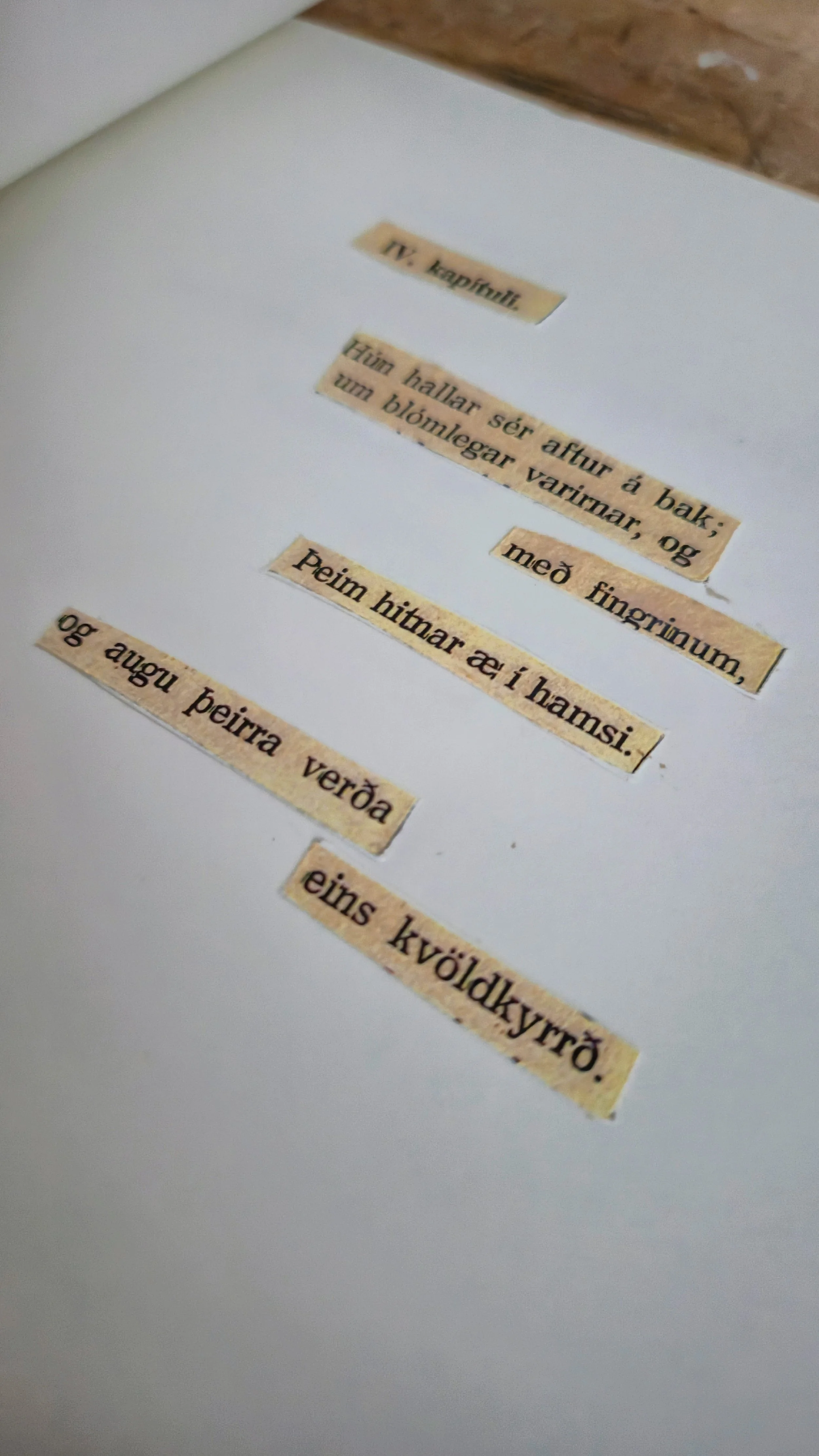A white surface with torn pieces of paper with handwritten text in Icelandic, placed in a scattered manner.