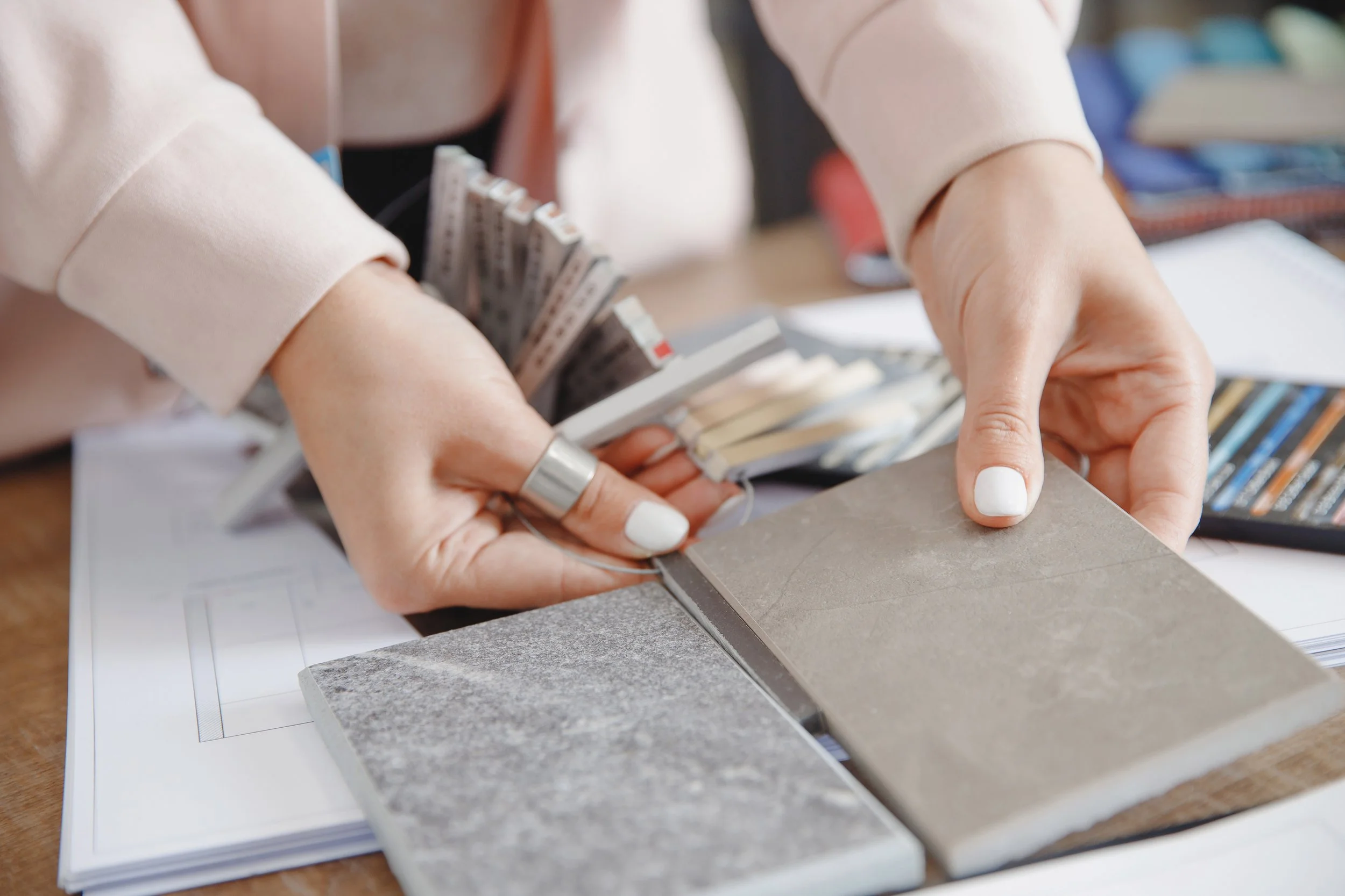 KBC Designer holding color sample cards and tile samples.