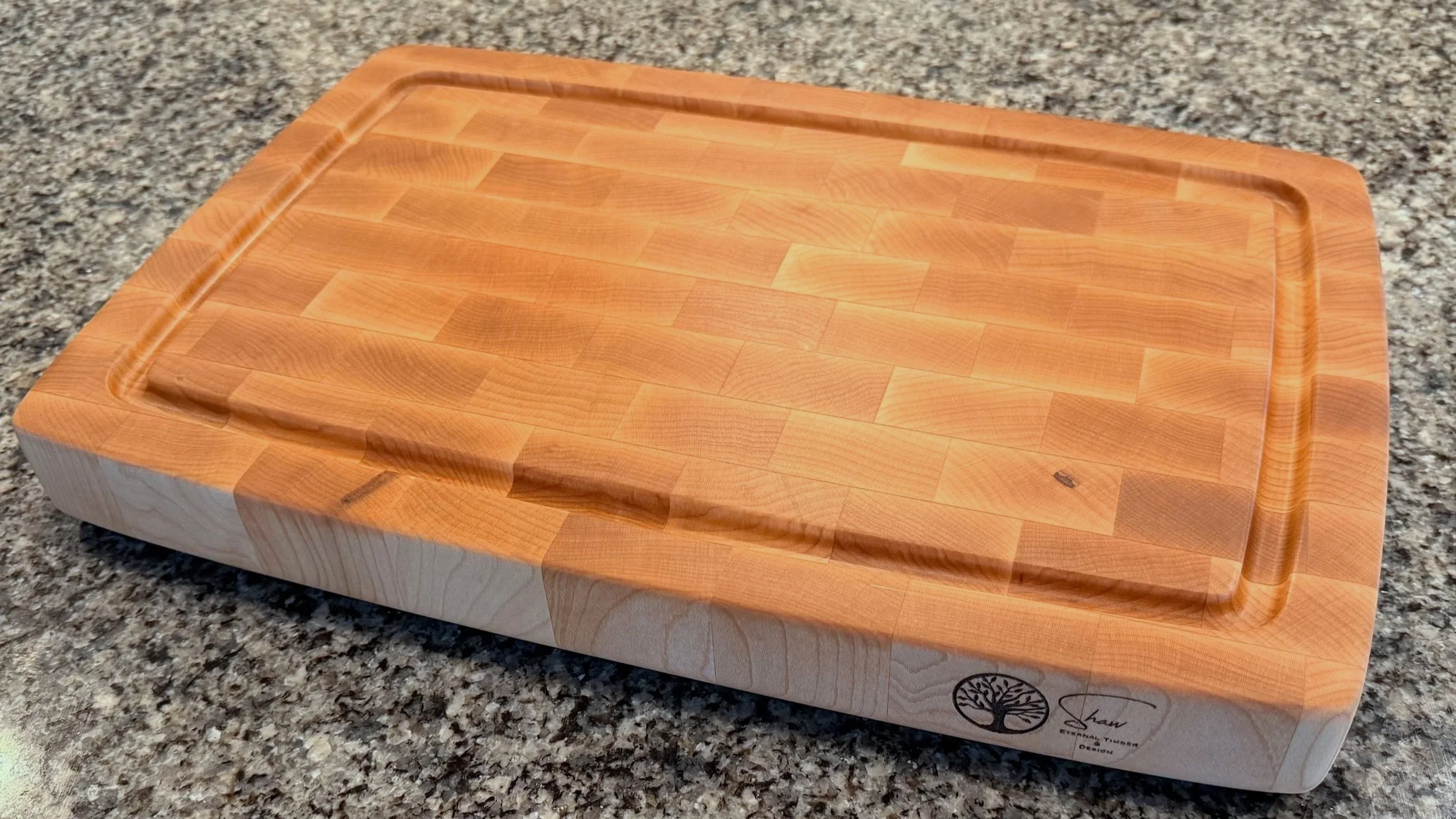 Custom maple end-grain cutting board with juice groove on granite countertop