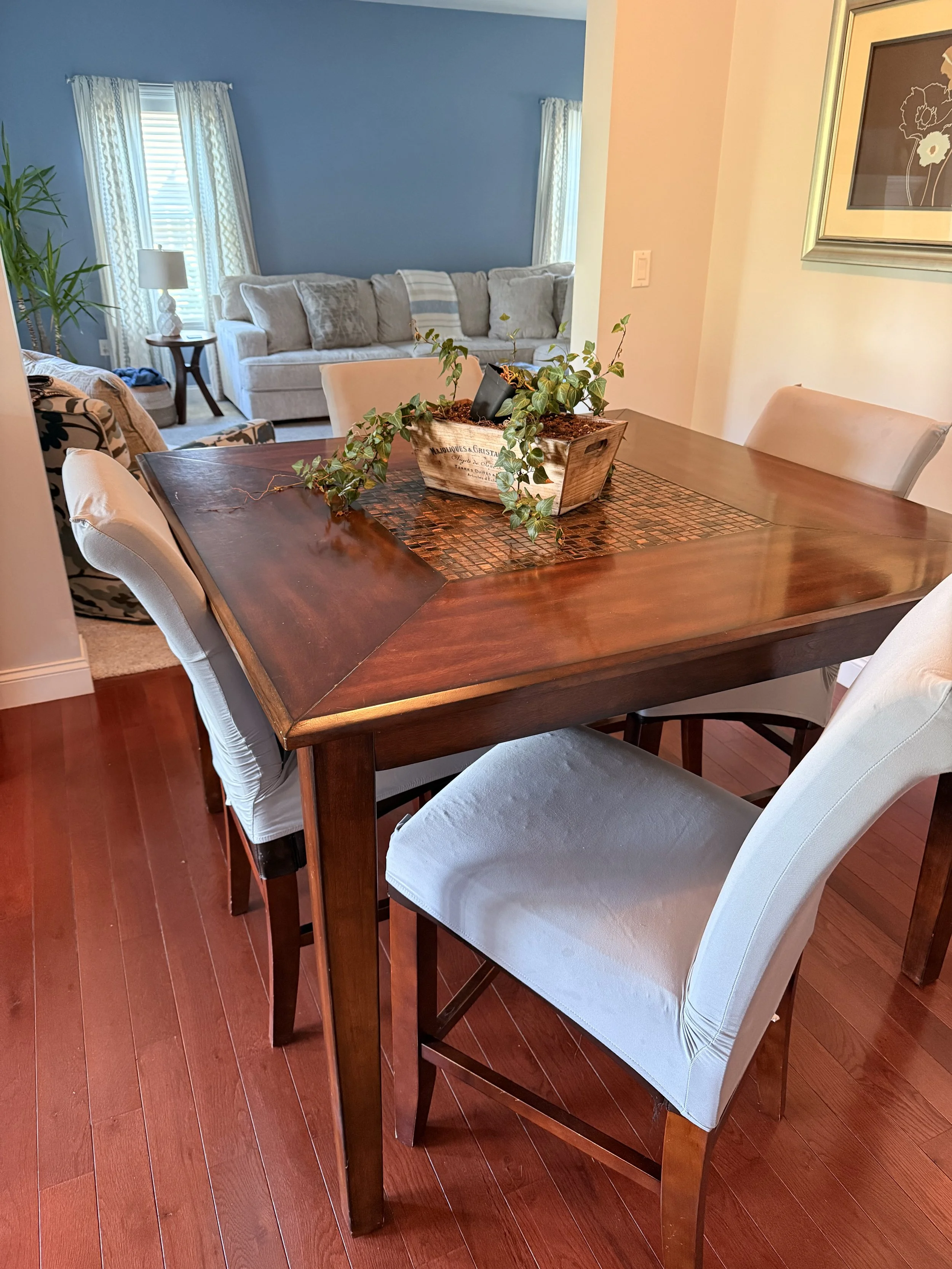 The current breakfast table. Walnut-stained wood that picks up red tones, with white slipcovered chairs on cherry hardwood floors. The table that needs replacing.