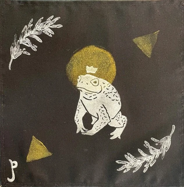 white frog with gold halo against black backdrop
