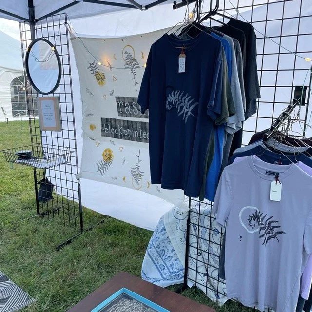 grids holding fern t-shirts at an outside market