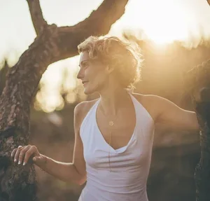 Woman stretching outdoors near a tree during sunset