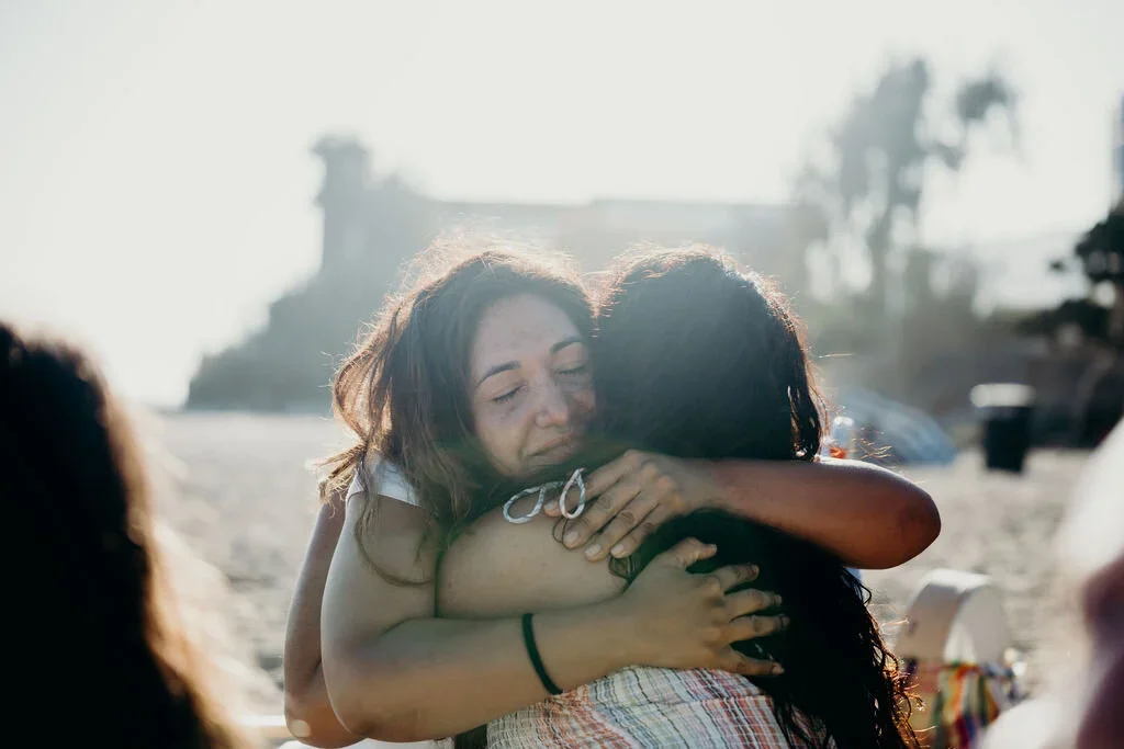 Two women hugging each other on a beach.