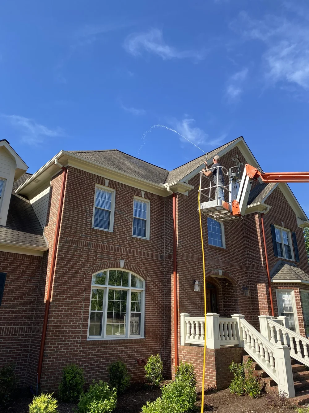 Apex Soft Wash cleaning a shingle roof from a lift