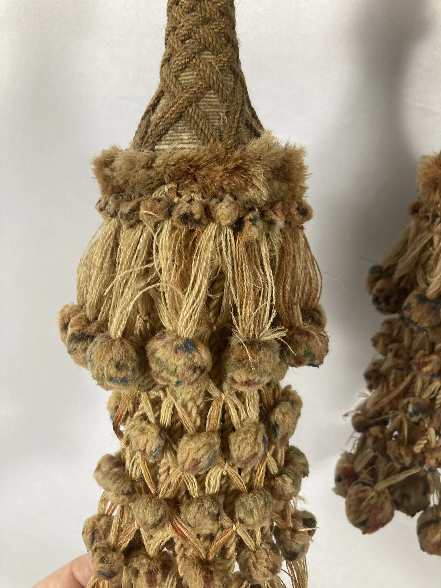 Pair of French passementerie tassel tiebacks hanging side by side, cream and tan with polychrome bobs