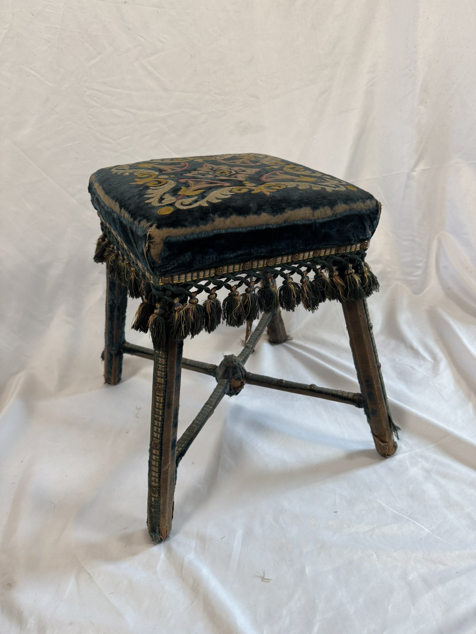 Embroidered seat of a blue velvet stool, viewed from above