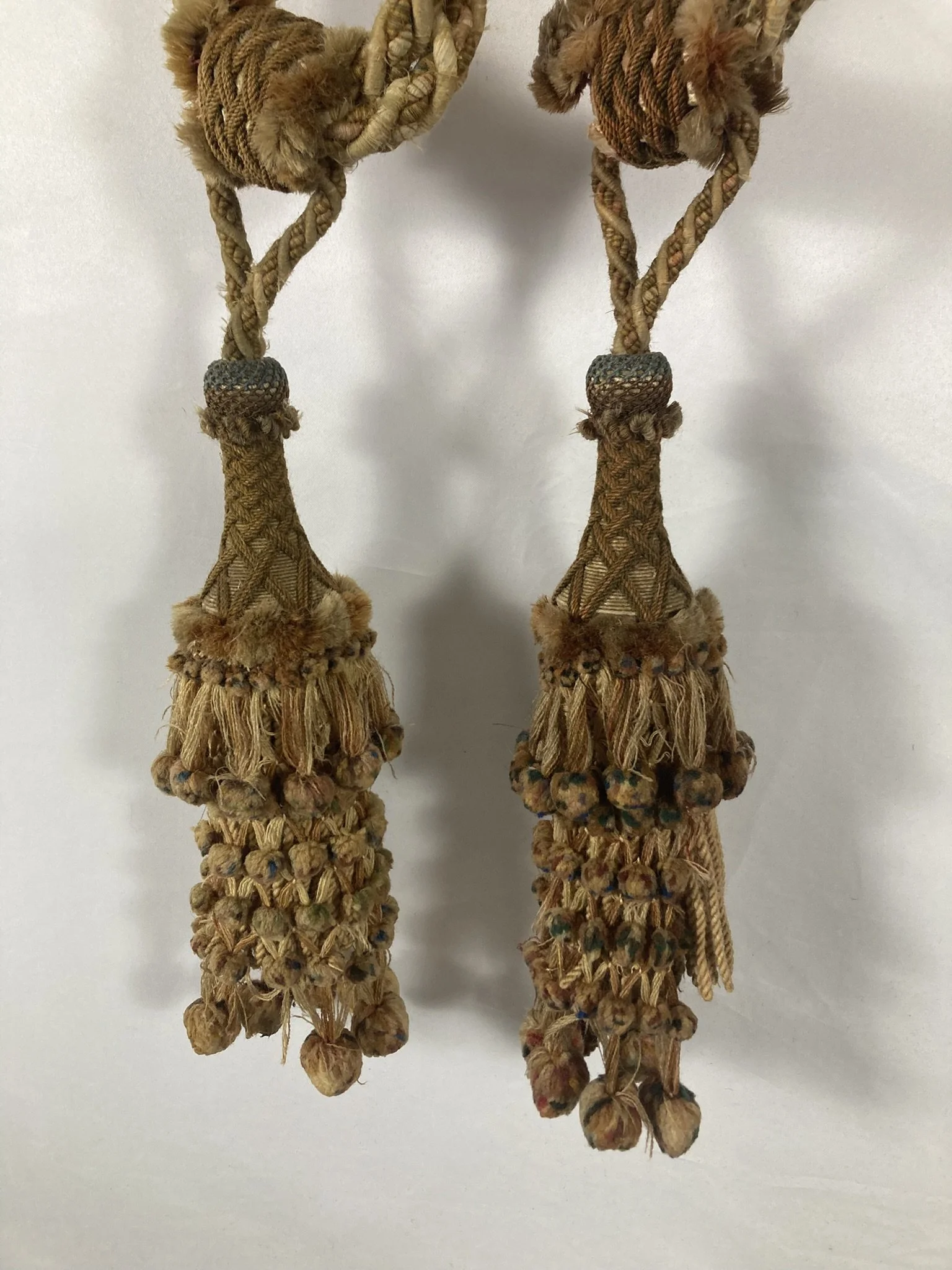 Pair of French passementerie tassel tiebacks hanging side by side, cream and tan with polychrome bobs