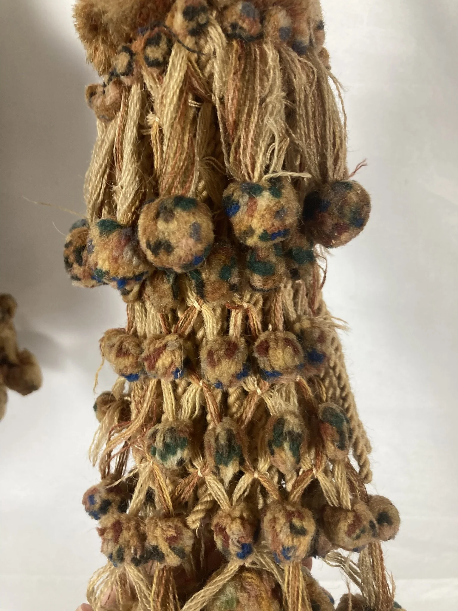 Pair of French passementerie tassel tiebacks hanging side by side, cream and tan with polychrome bobs
