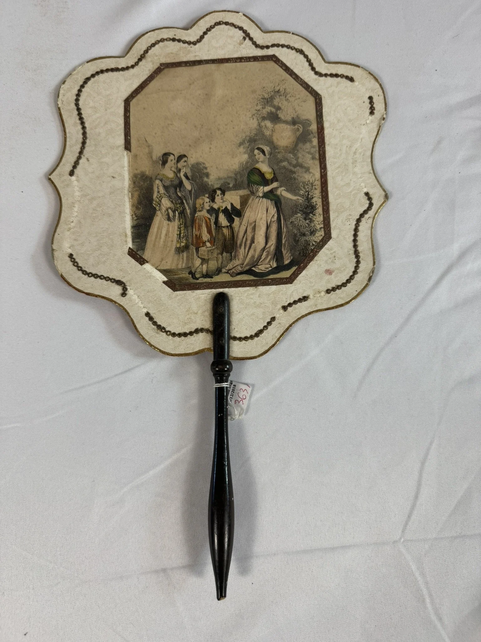 Antique French hand fire screen, ecran a main, Romantic period c.1840, full view, scalloped lobate outline, ivory ground, bead-chain swag decoration, hand-coloured lithograph, ebonised handle