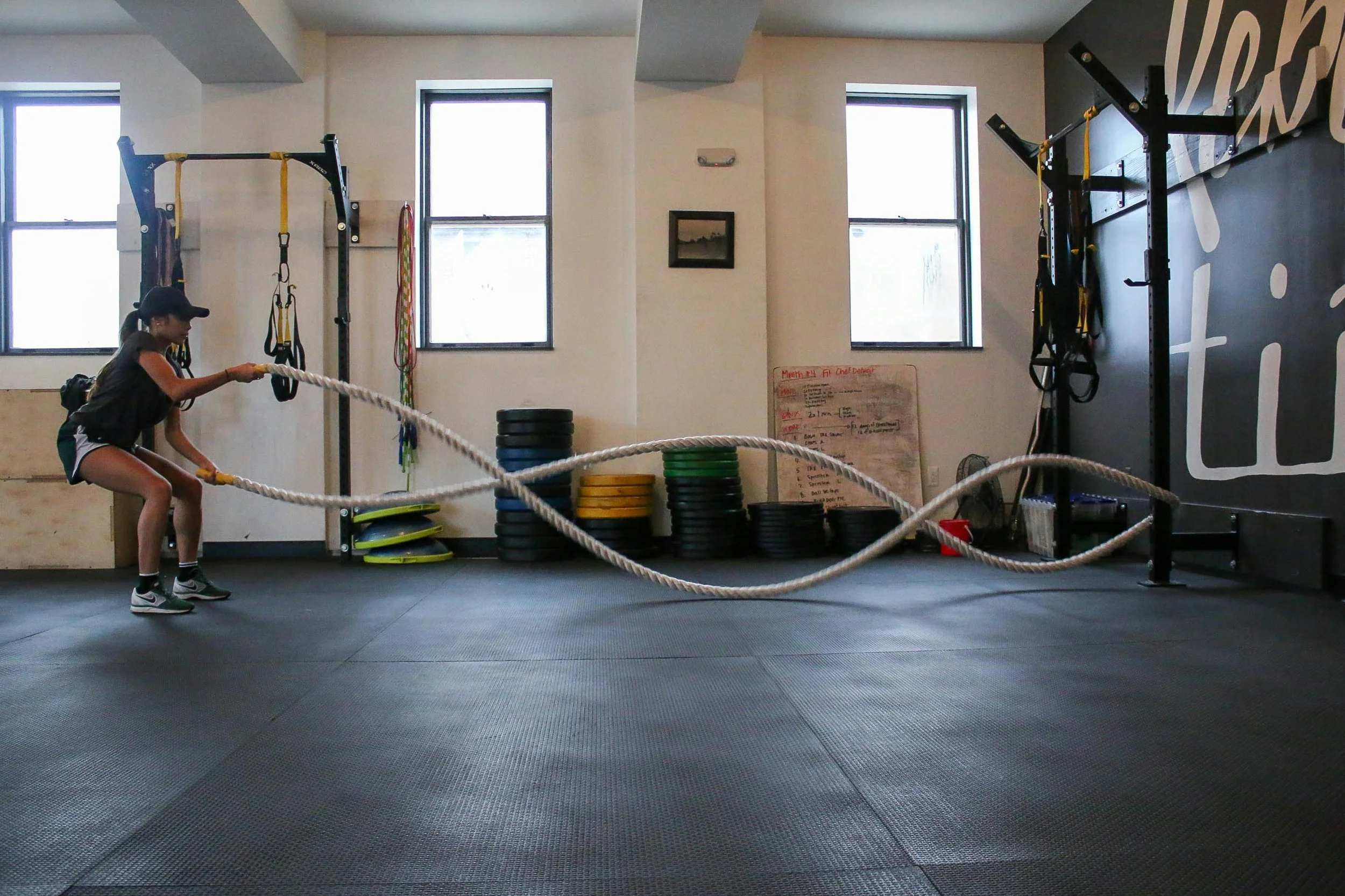 Woman in gym setting using large ropes to workout