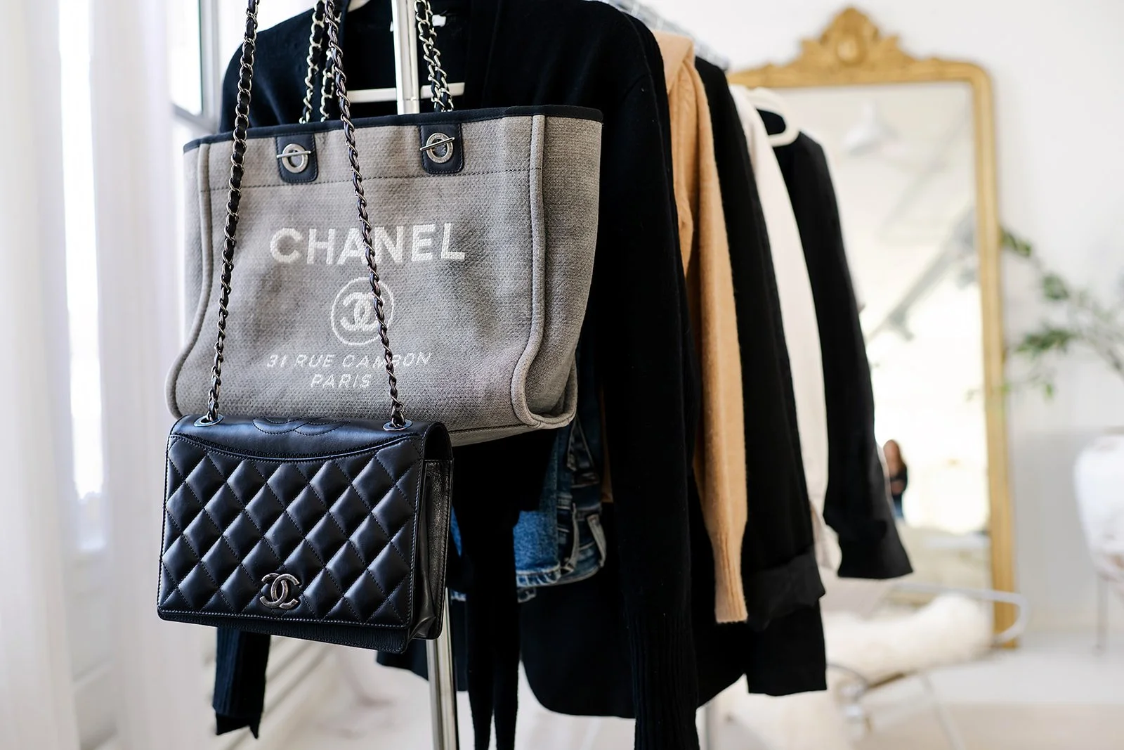 Two women sitting at a marble table, looking at a laptop and smiling, with a mirror in the background