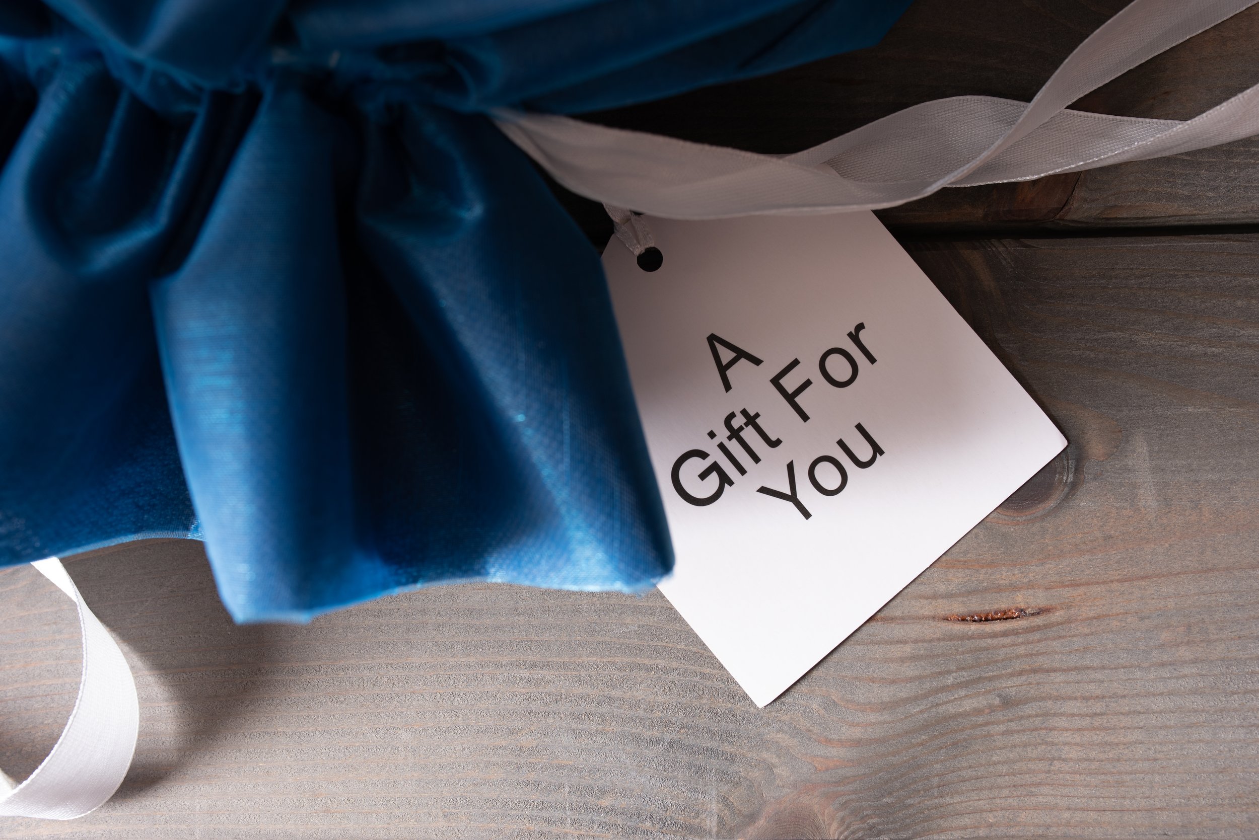 blue-gifts-sack-with-text-card-on-wooden-backgroun-2023-11-27-05-21-23-utc.jpg