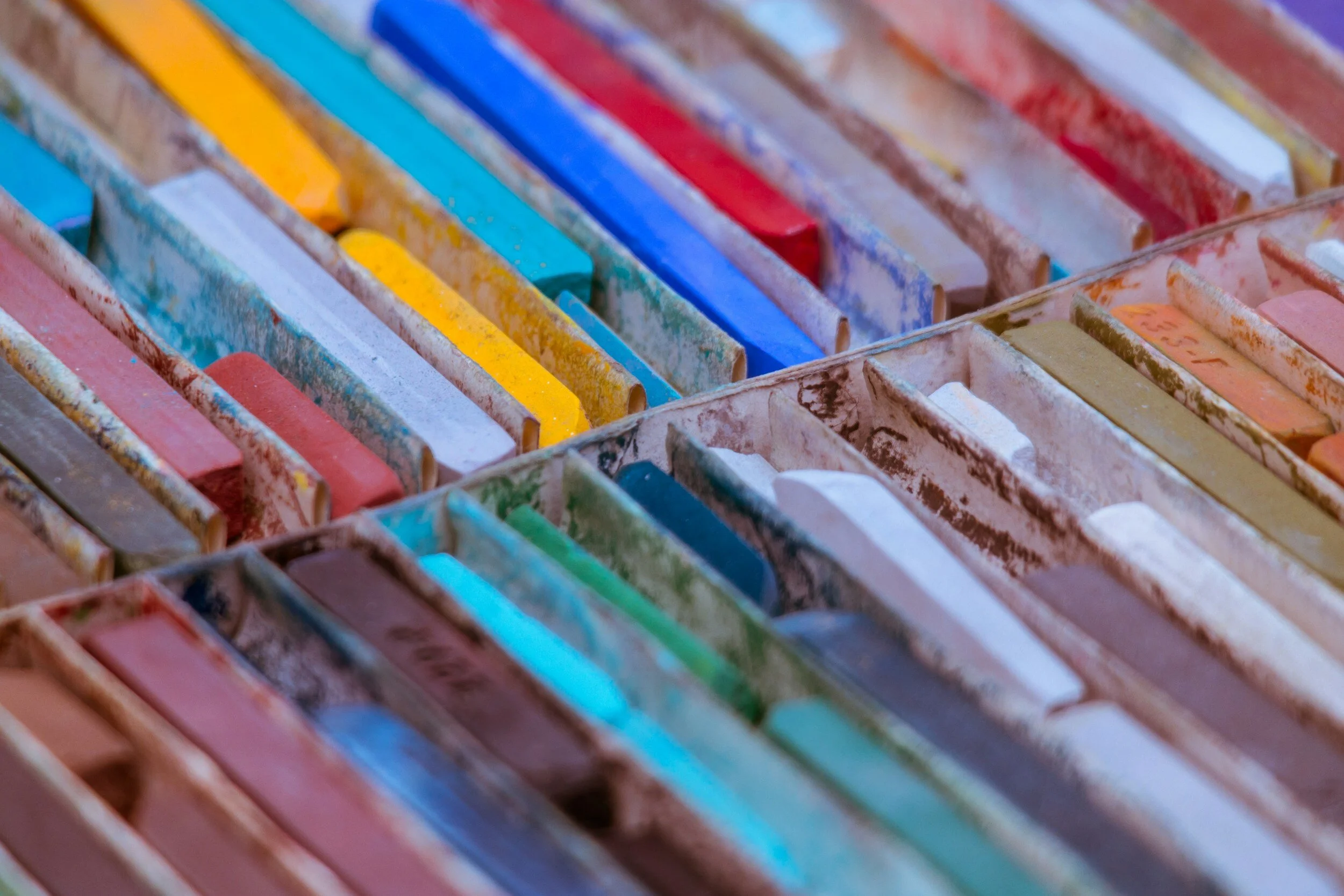 A close-up of watercolor paints in various colors arranged in a box.