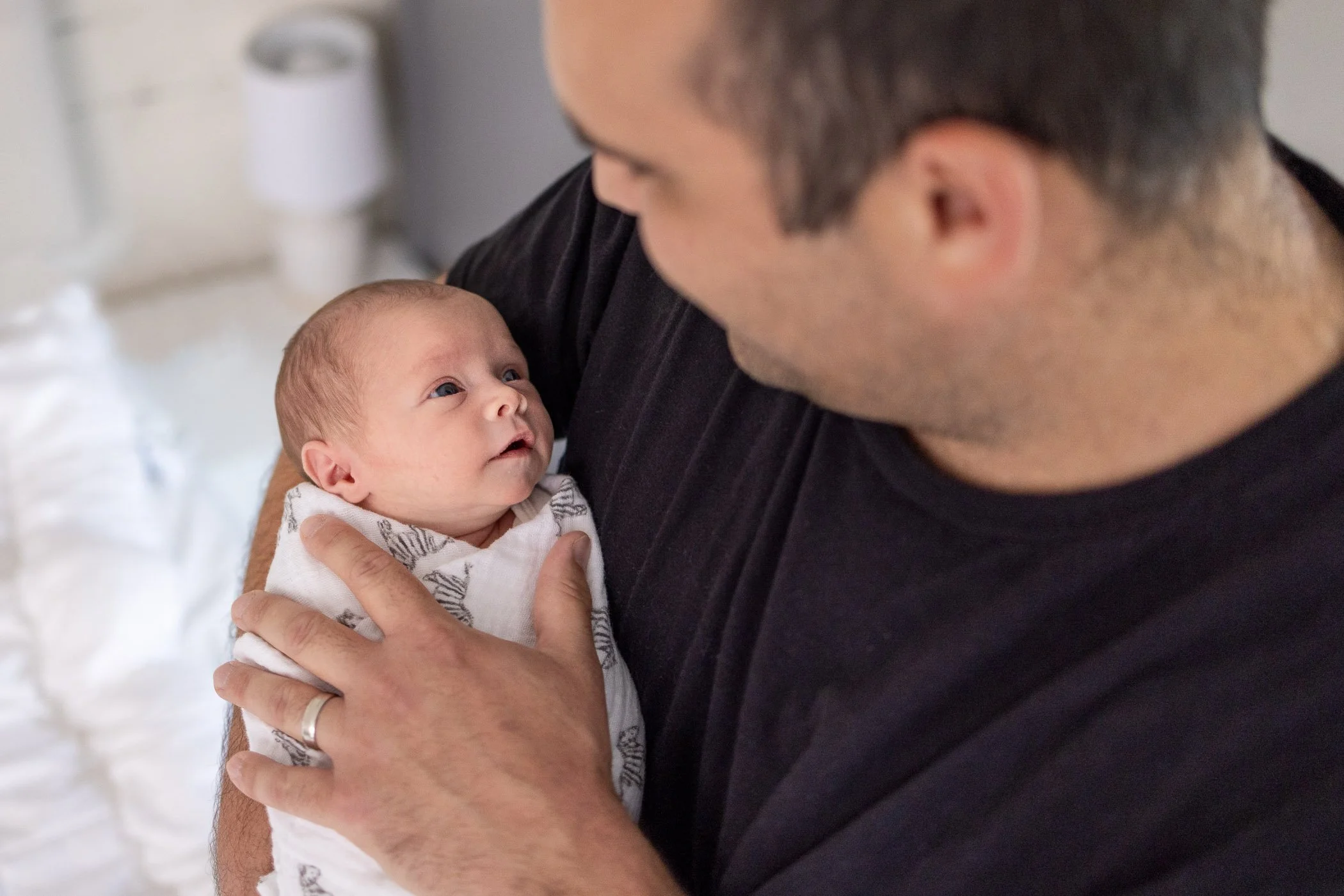Dad holding newborn daughter while gazing at each other