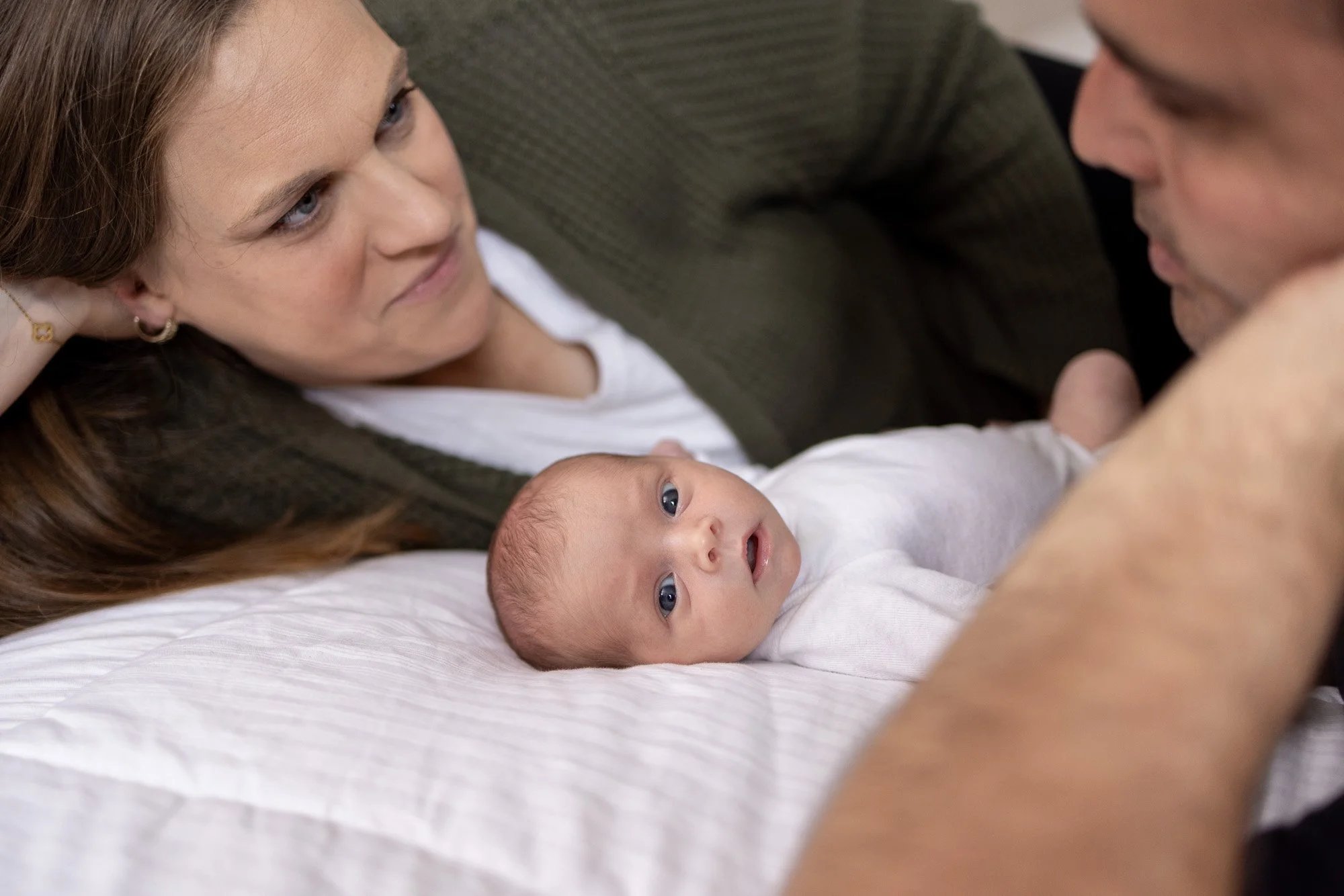 mom and dad laying on bed with baby girl.jpg