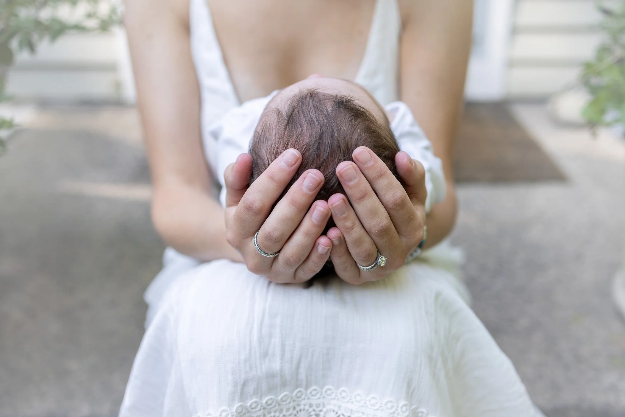 Mom's hands holding baby's head tenderly.