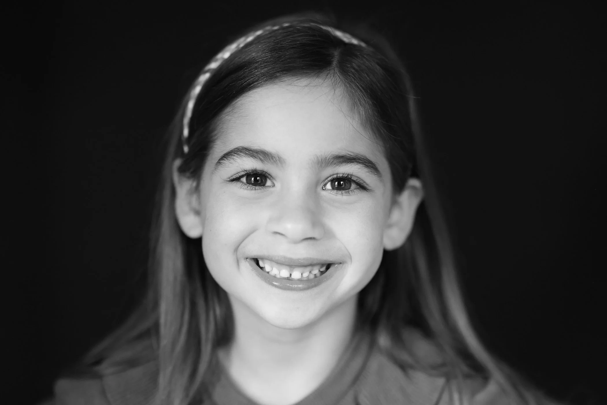 black and white of smiling little girl wearing headband